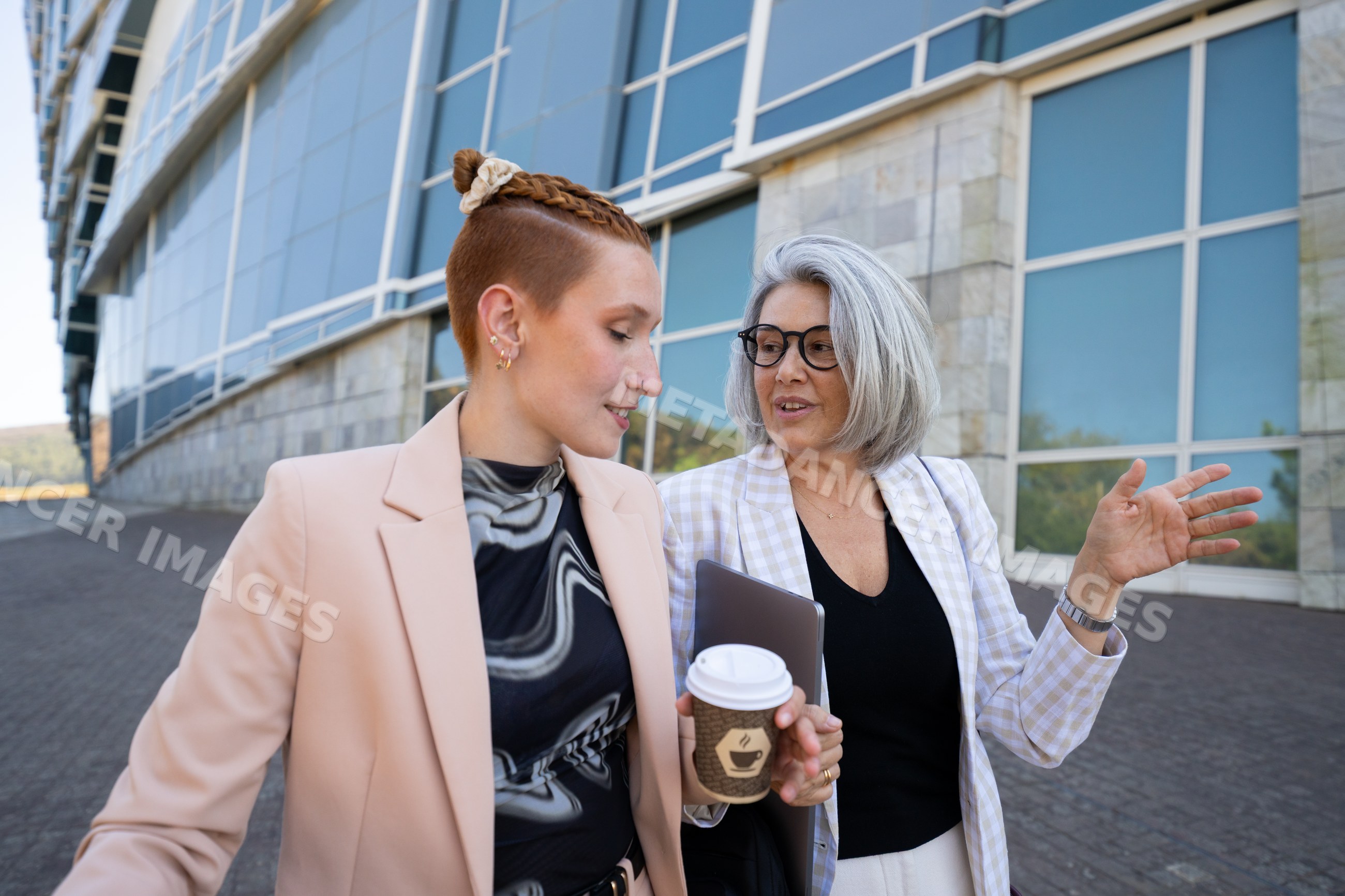 Businesswomen walking and talking outside modern office building