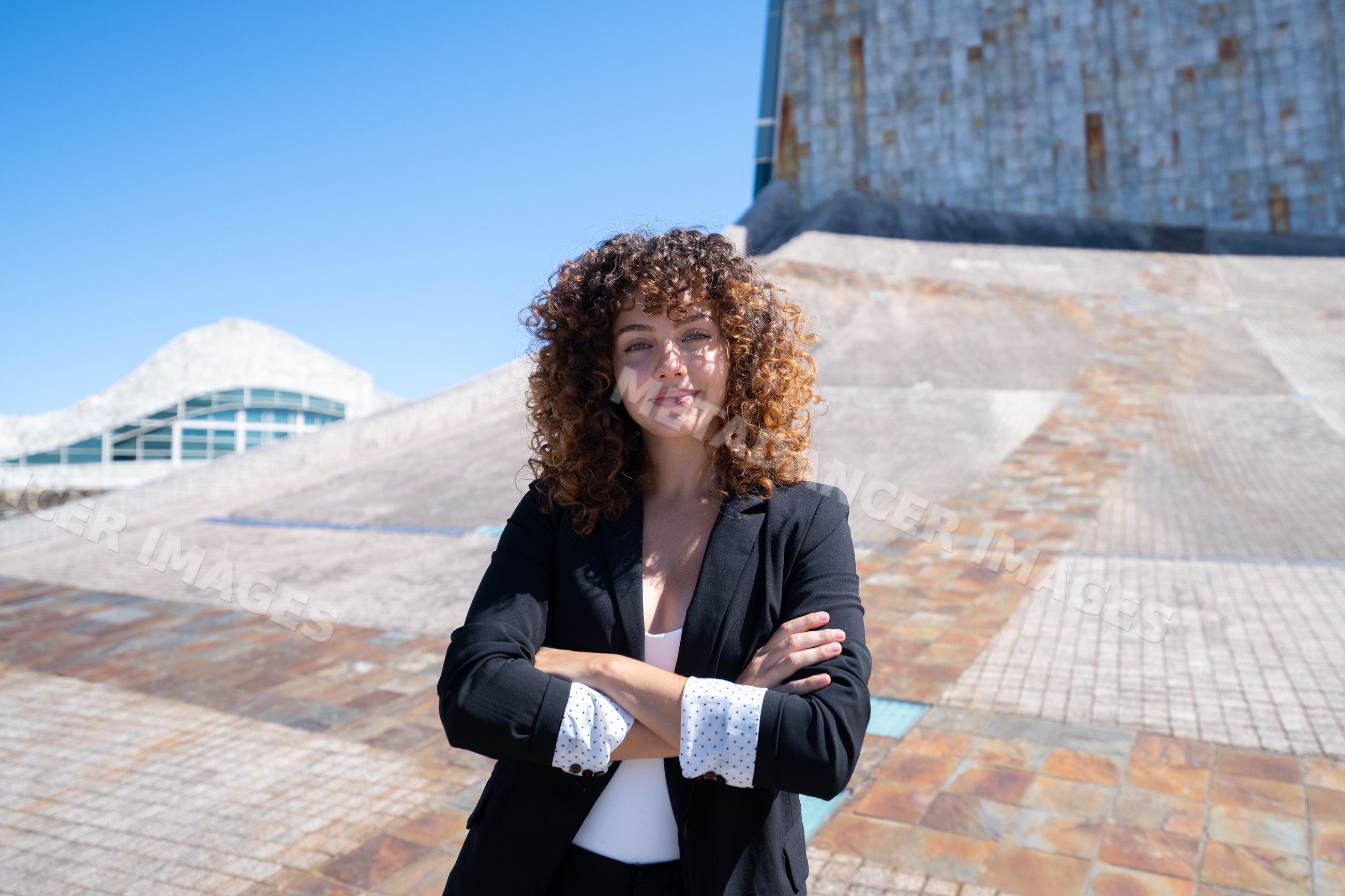 Businesswoman with curly hair posing confidently outdoors