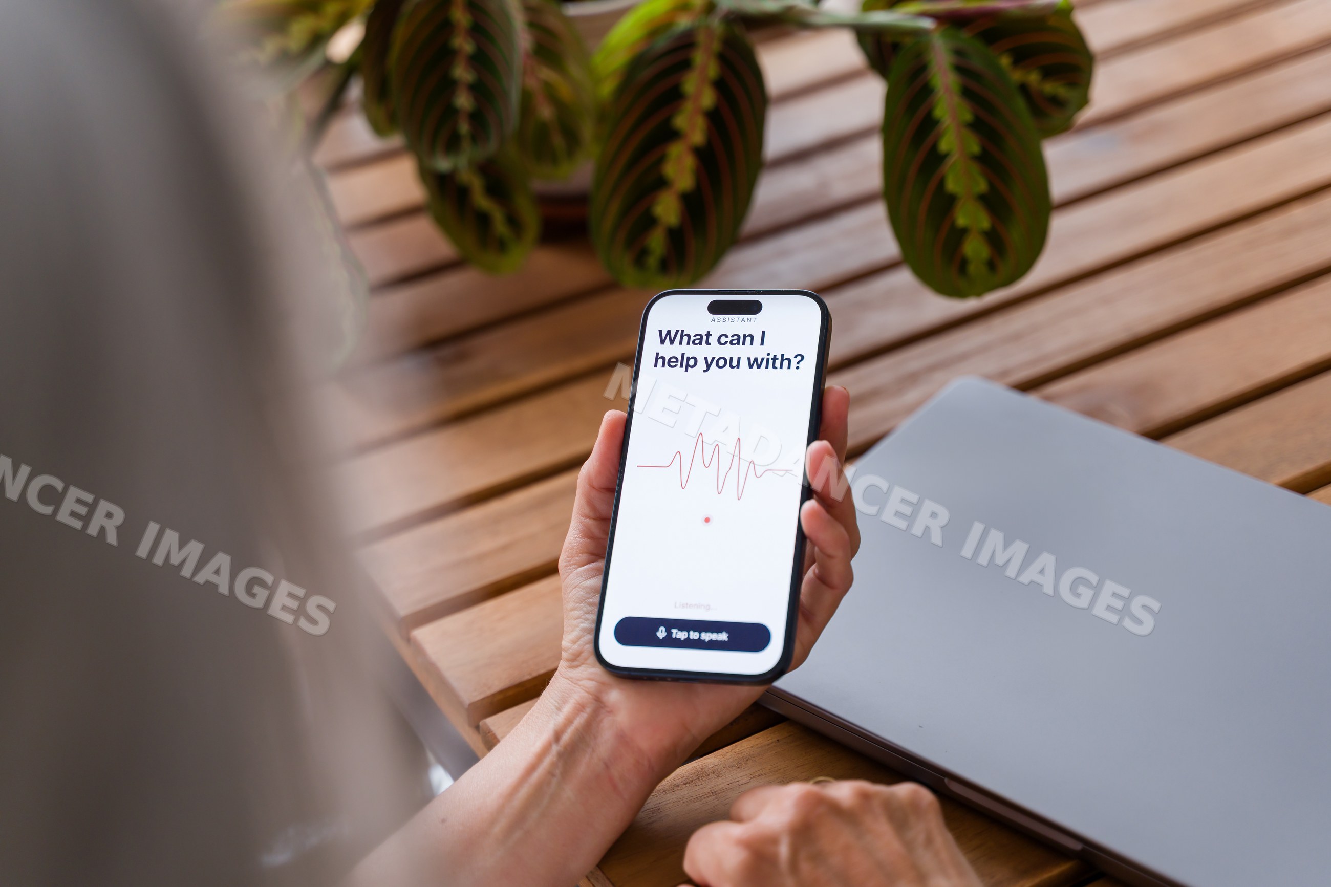 Smartphone with voice assistant interface shown over wooden table