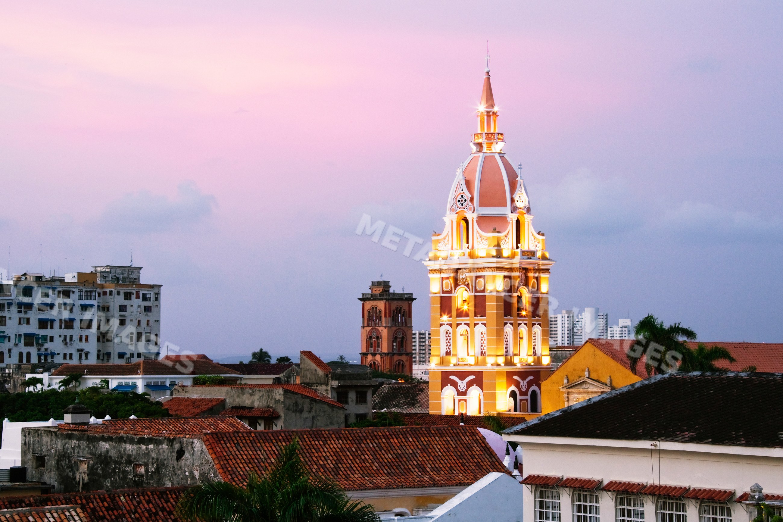 Cartagena cathedral tower illuminated at dusk over rooftops