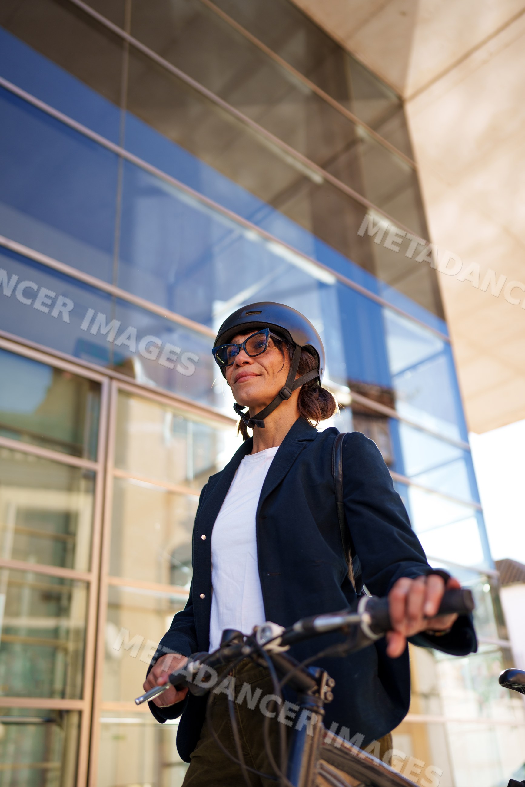 Hispanic woman holding bicycle outside glass building