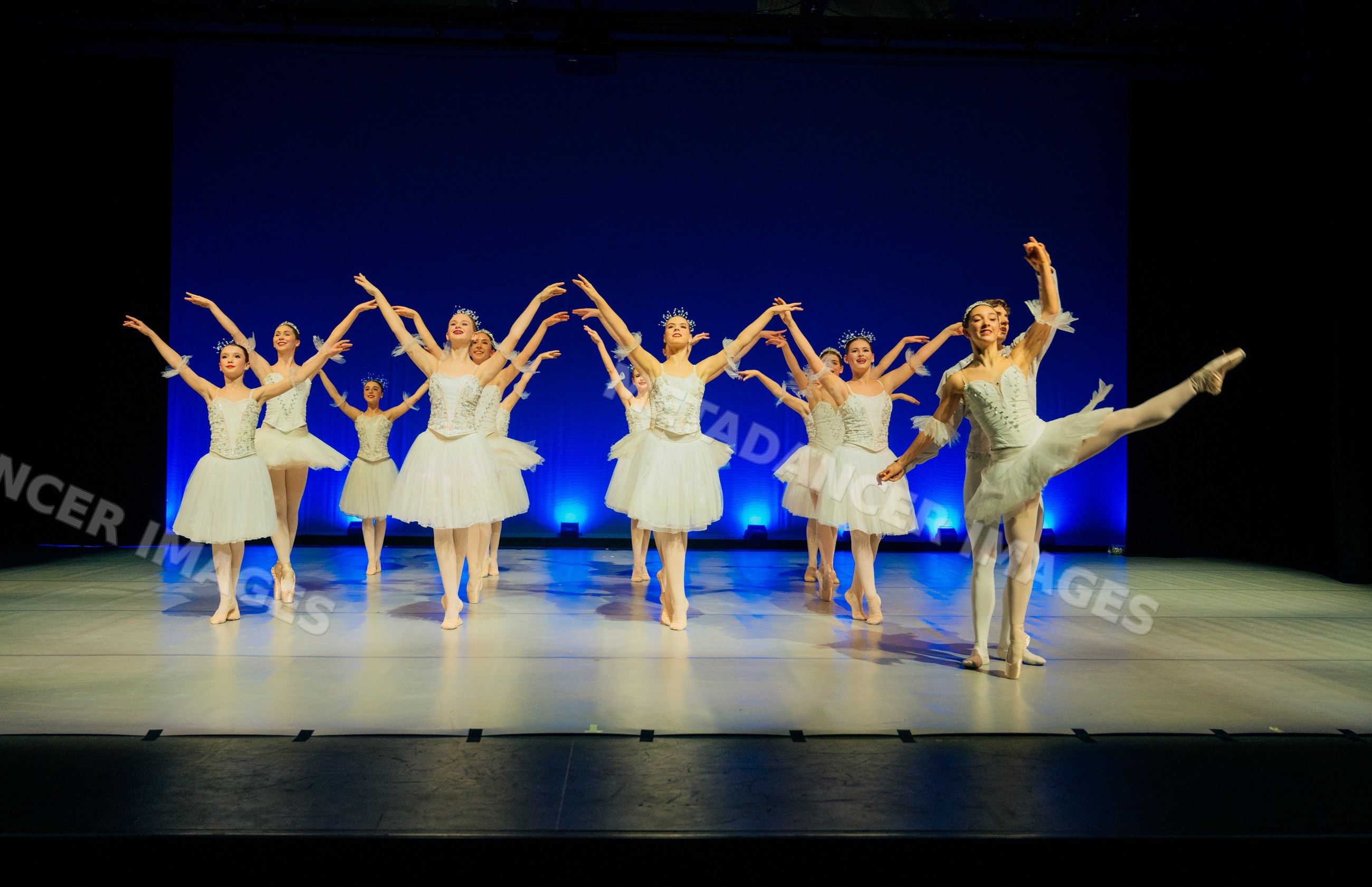 Ballet dancers perform holiday-themed dance on stage in white tutus