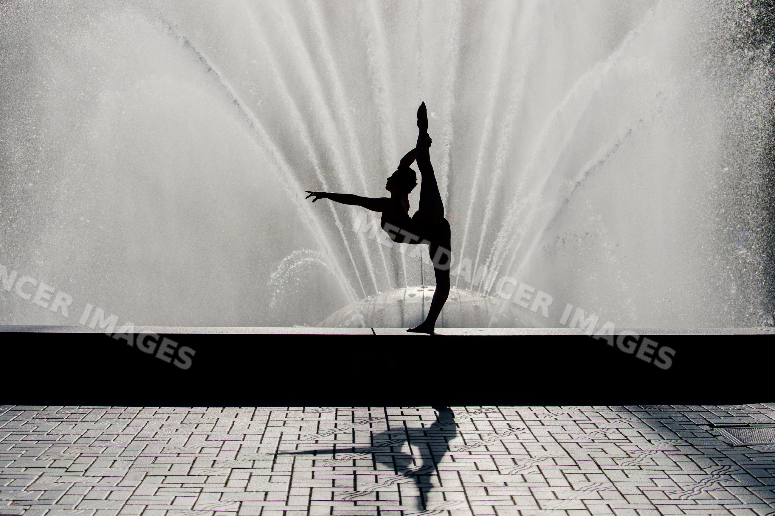 White dancer stretching leg before water fountain outdoors