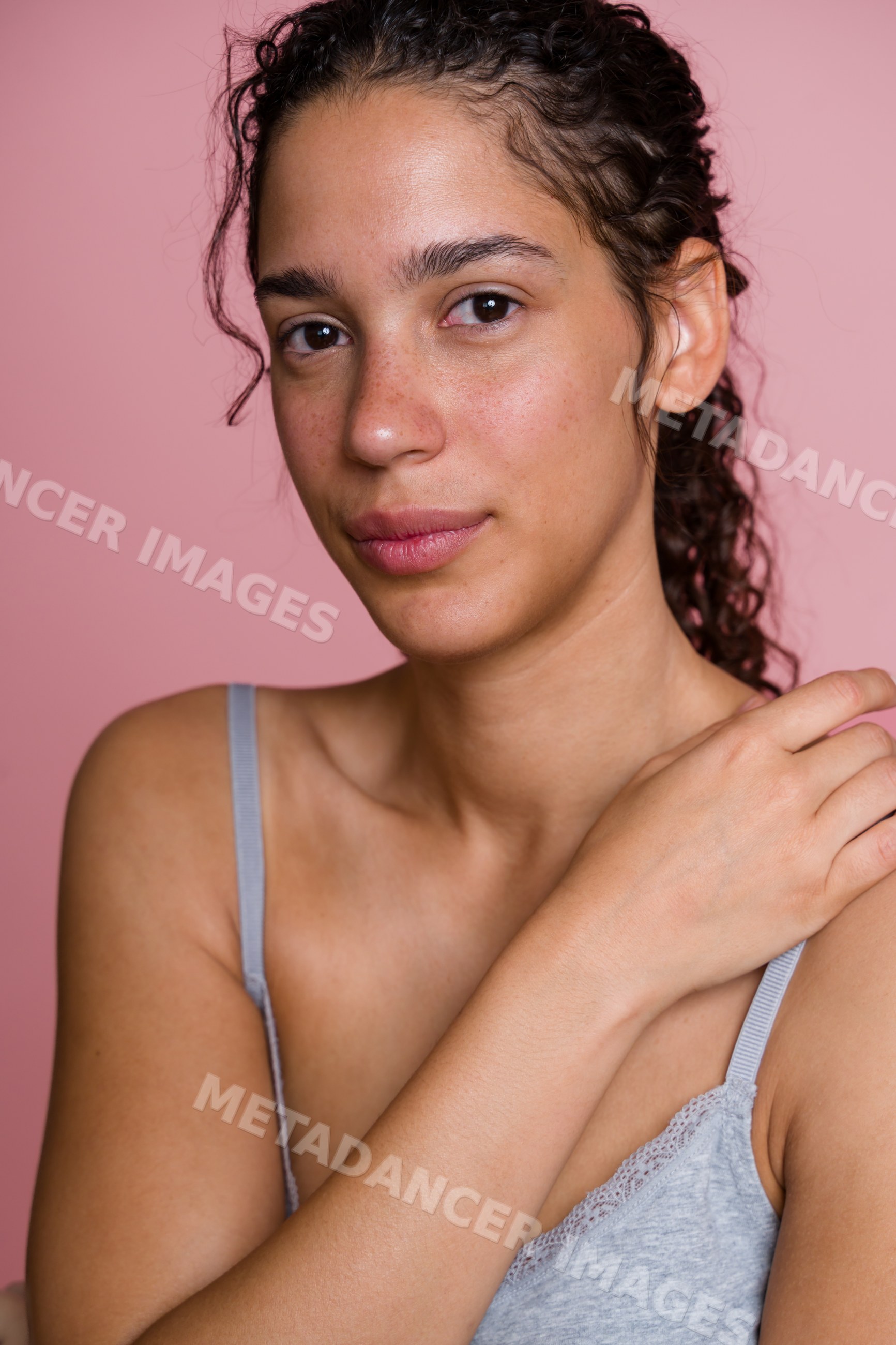 Portrait of Hispanic woman with natural skin against pink background