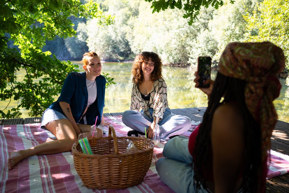 Friends enjoying a picnic by the river on a sunny day