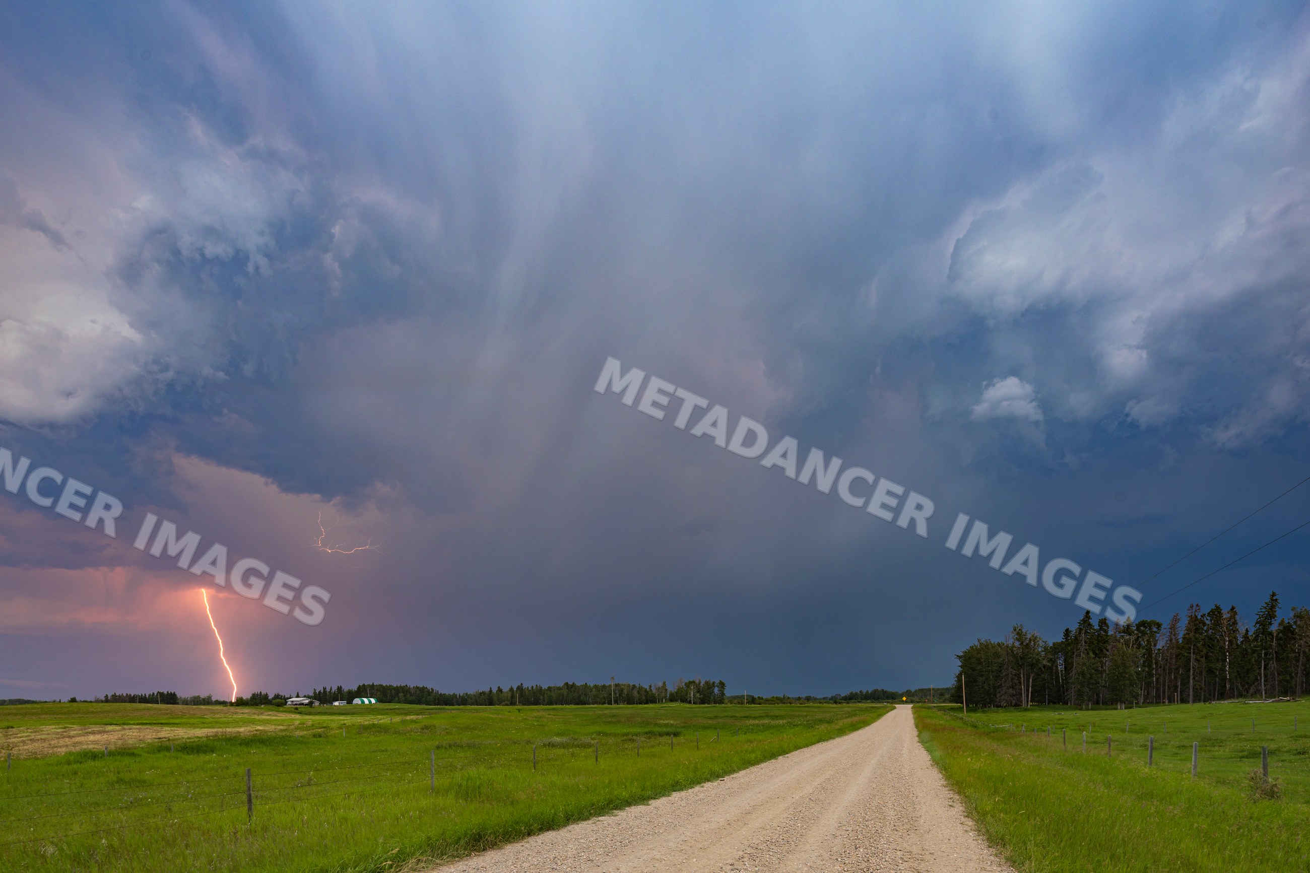Lightning striking farm road with stormy skies