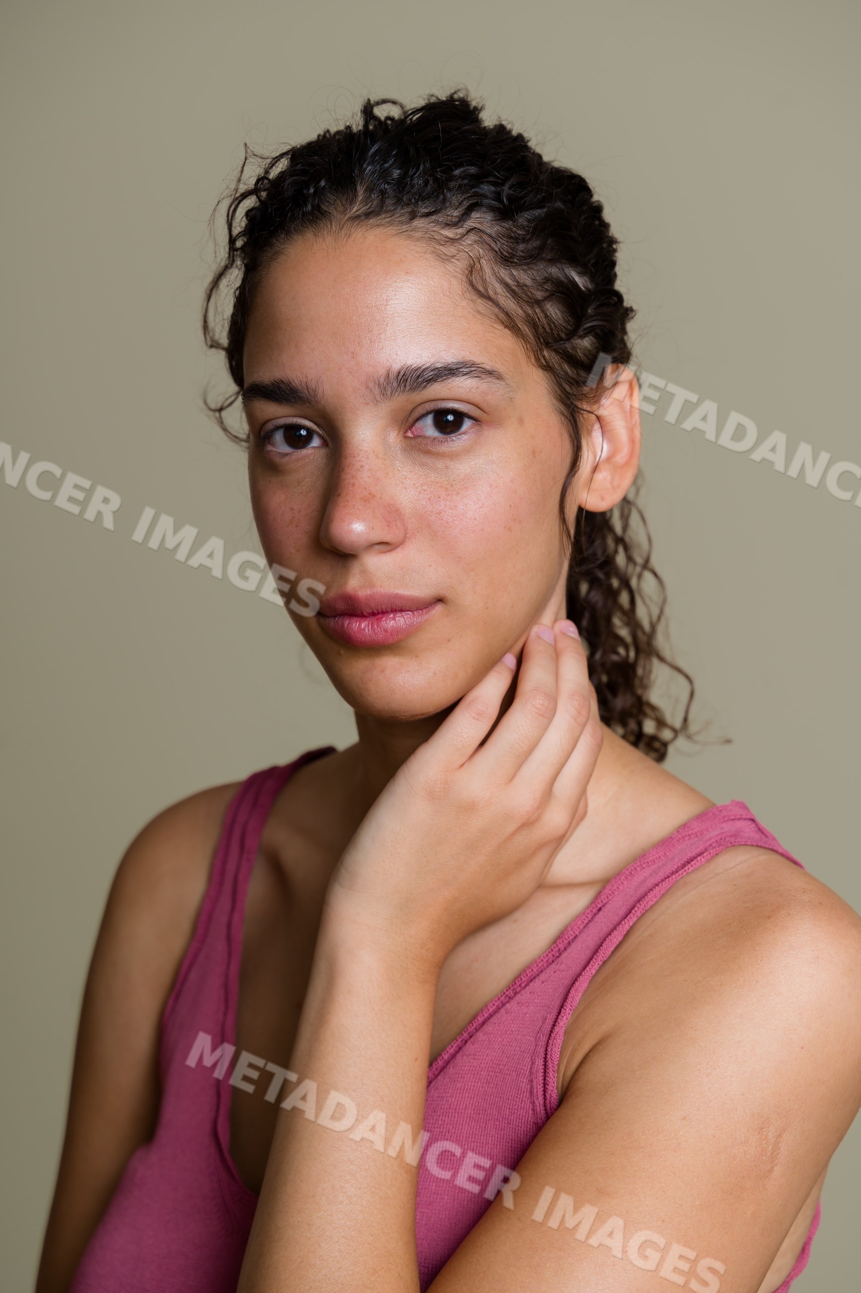 Portrait of Hispanic woman with curly hair touching neck
