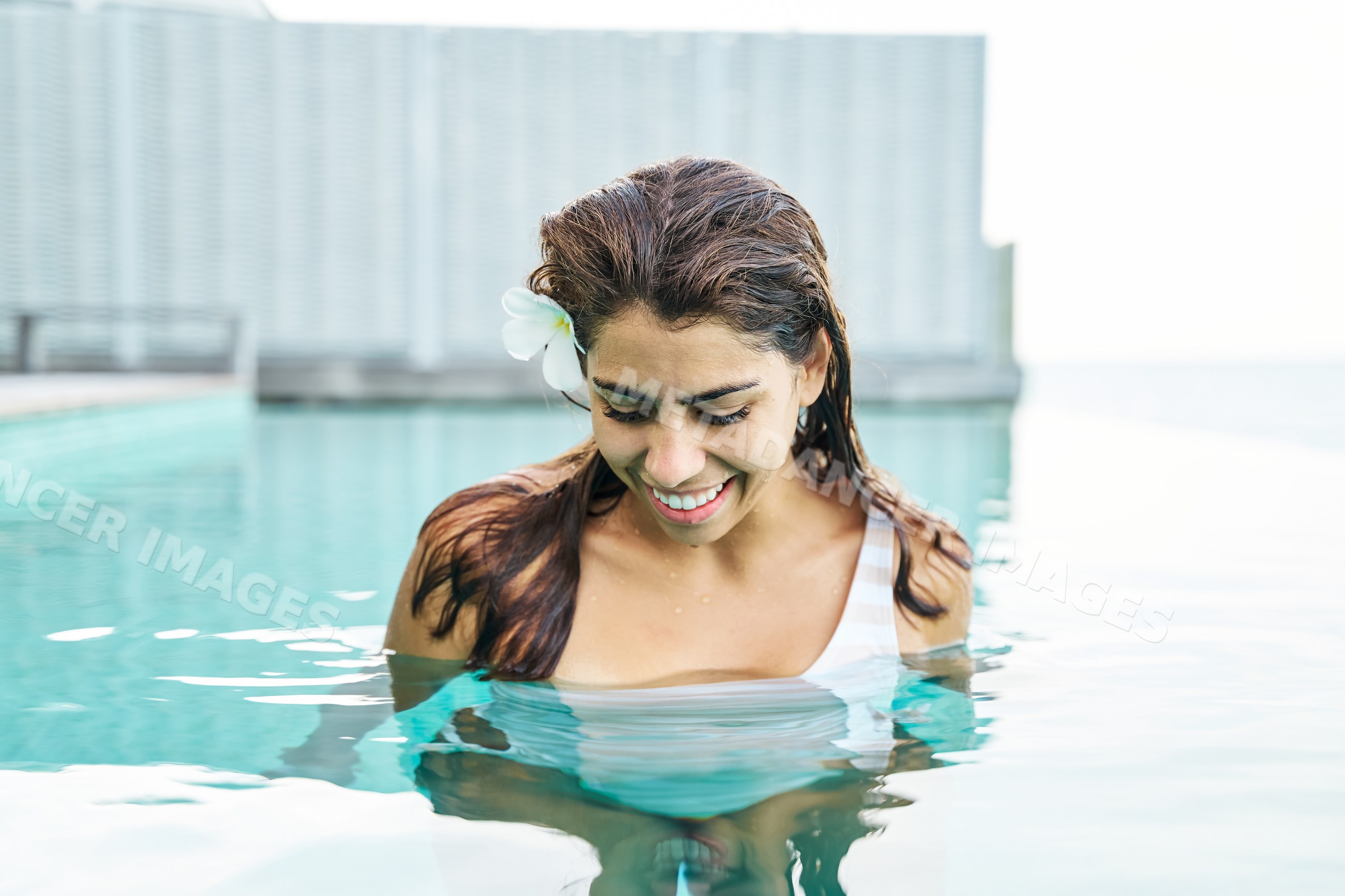 A white woman smiles while standing in an outdoor swimming pool