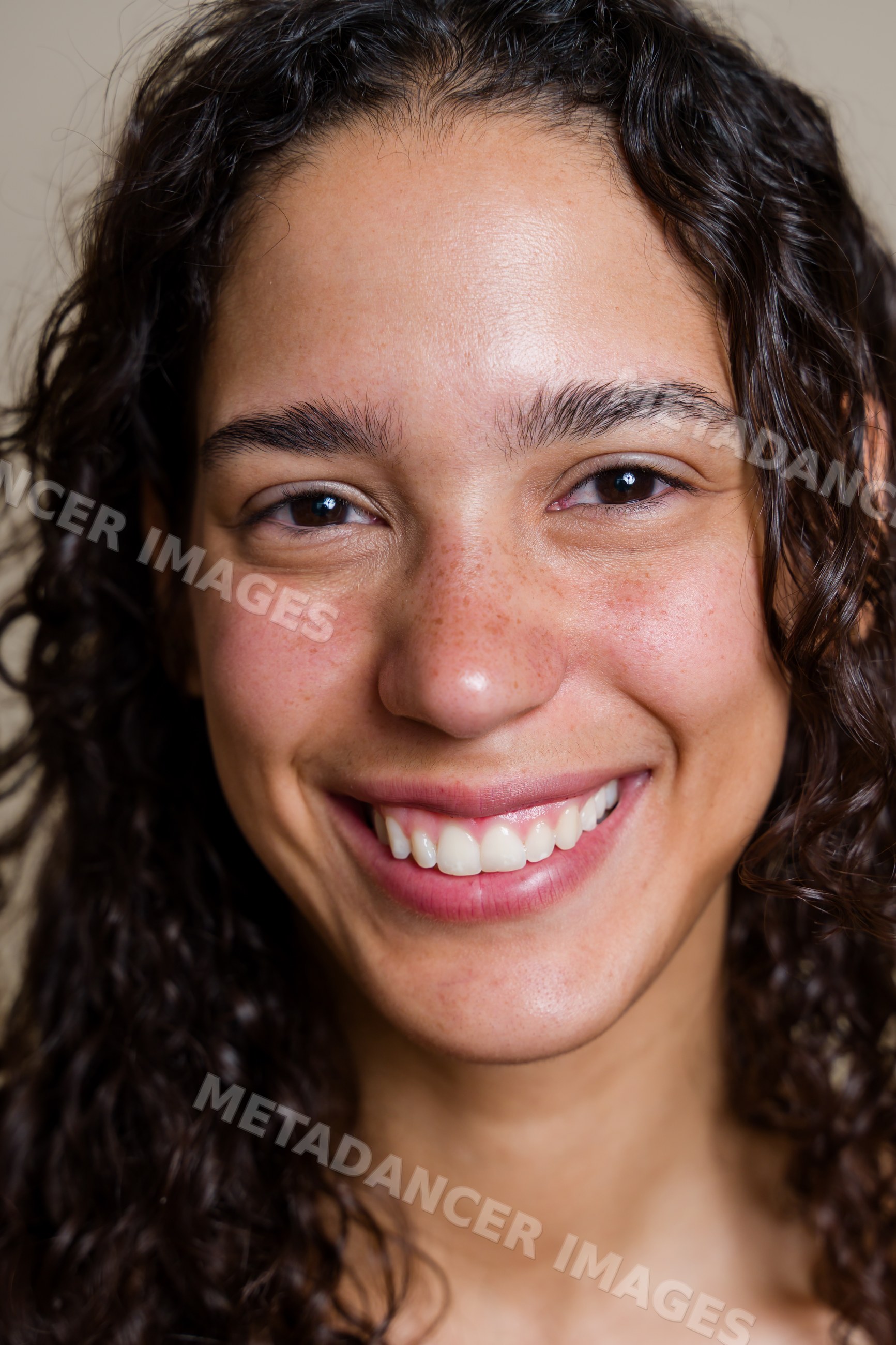 Smiling Hispanic woman with curly hair and freckles