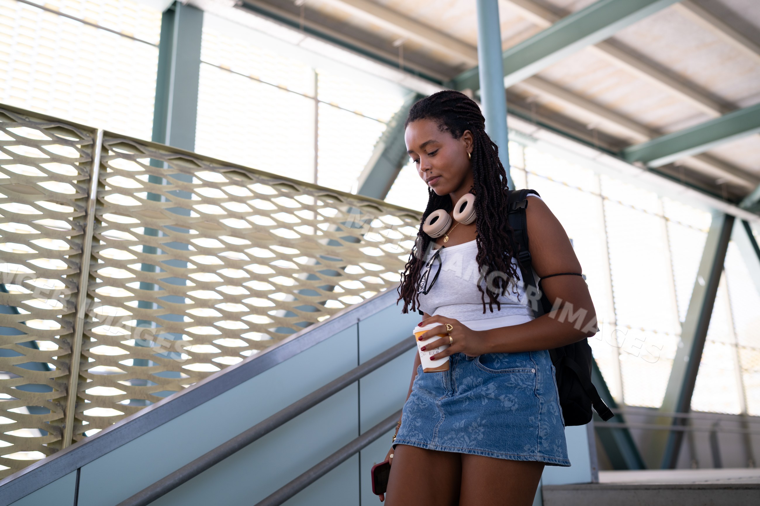 A young African American woman walks down stairs with coffee