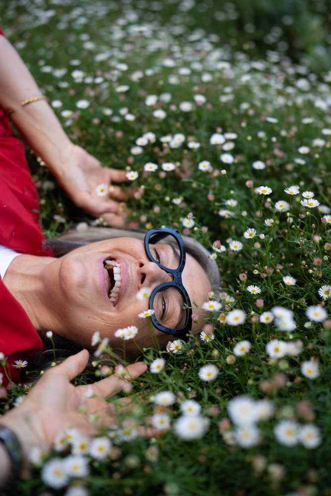 White woman lying happily in daisy flower field outdoors