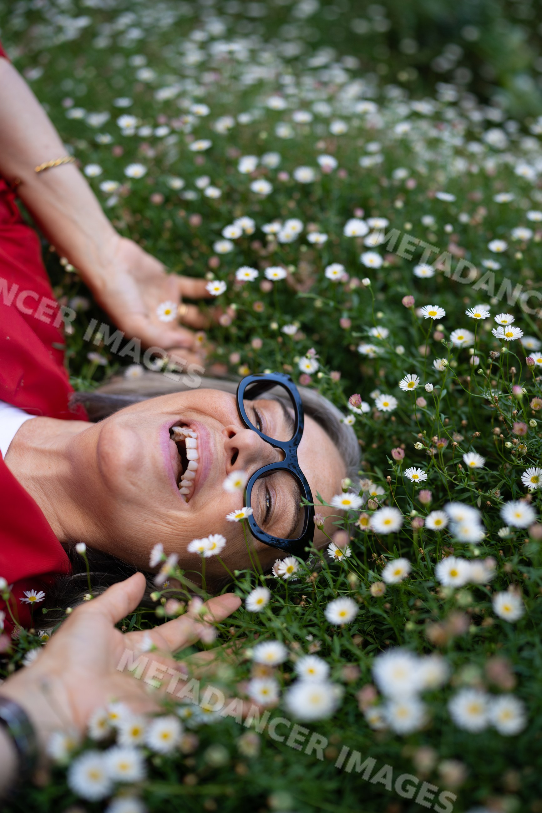 White woman lying happily in daisy flower field outdoors