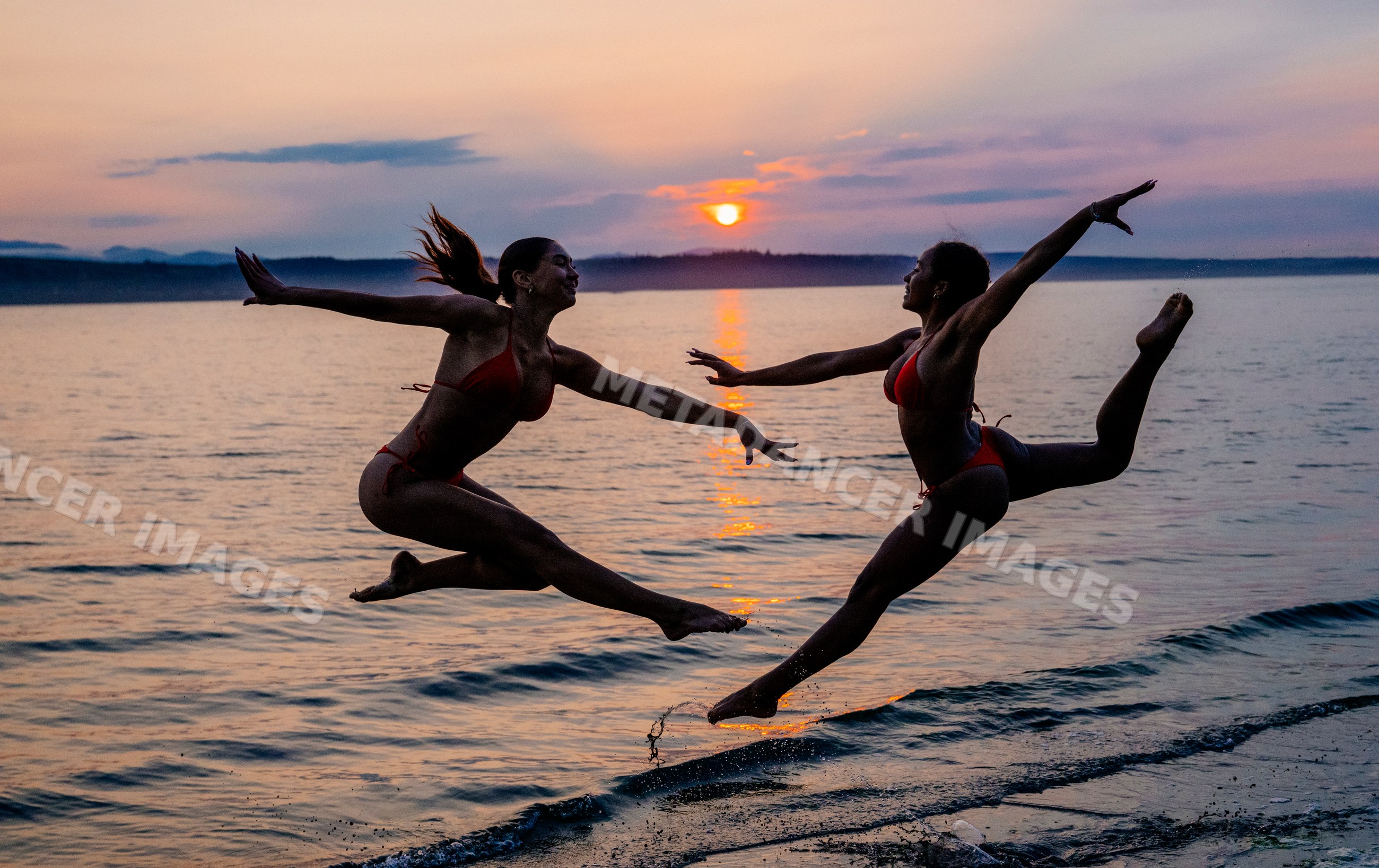 Two women performing partner acrobatics yoga at sunset on a beach