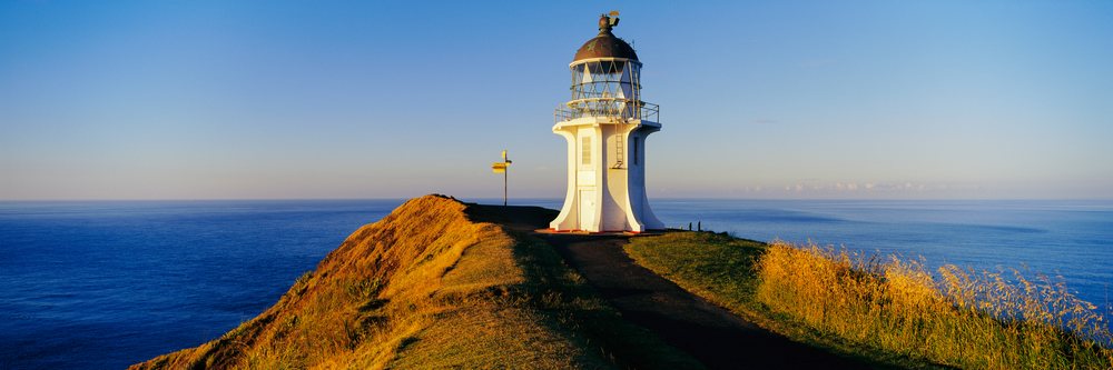 Lighthouse on coastal cliff overlooking ocean at sunset