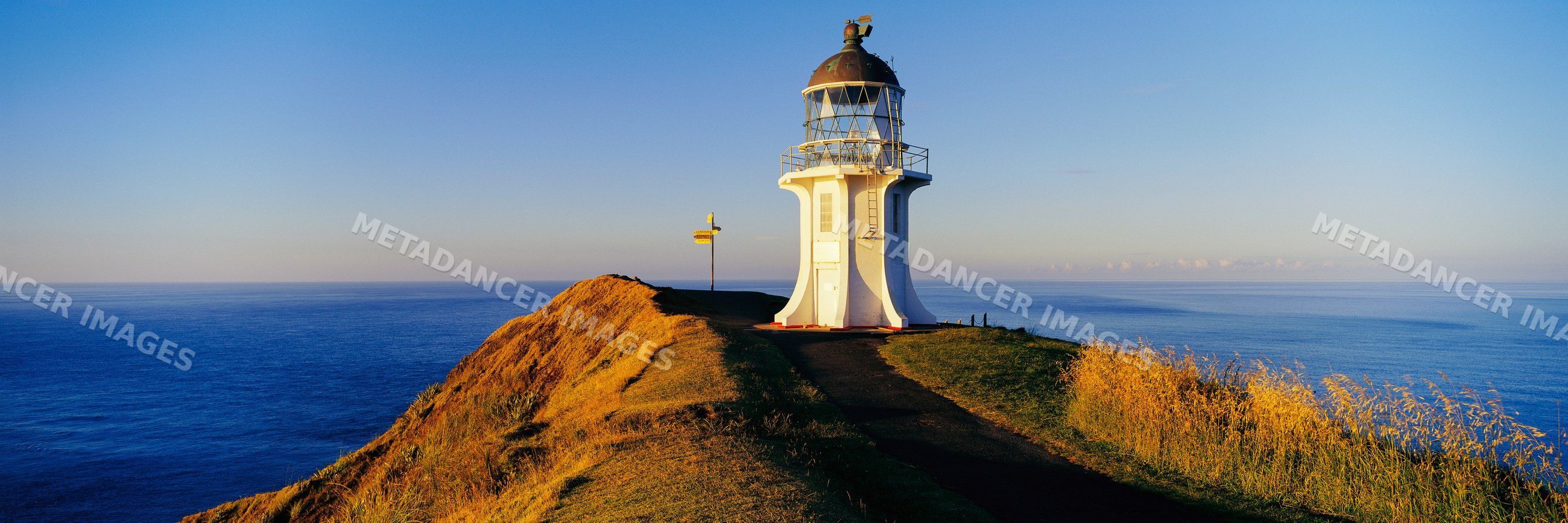 Lighthouse on coastal cliff overlooking ocean at sunset