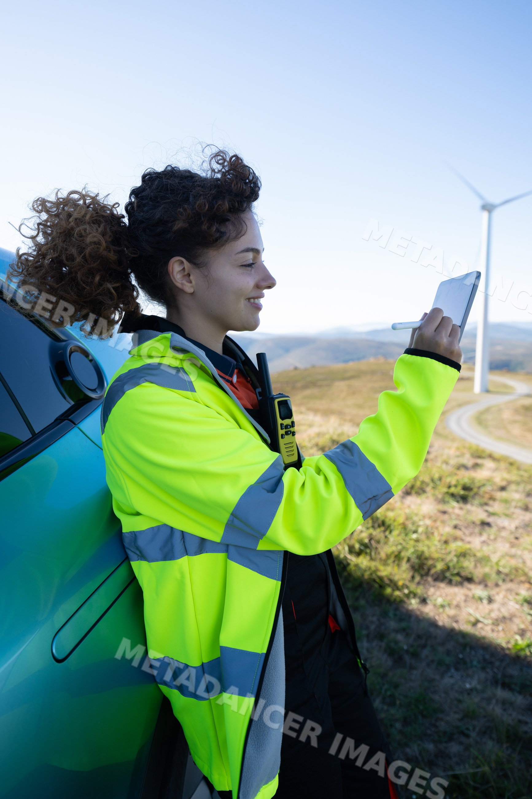 White woman using tablet at wind farm with wind turbines in Galicia