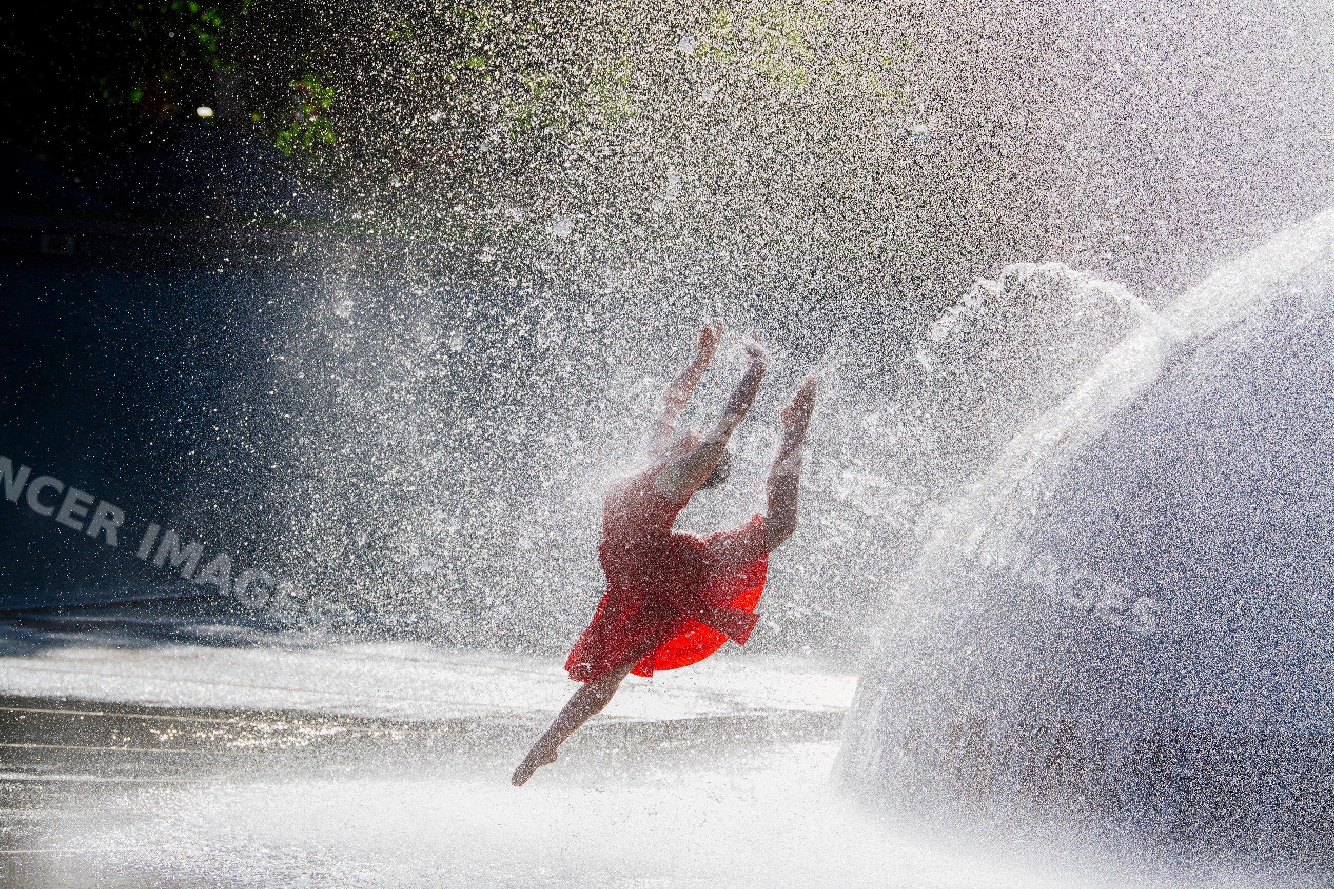 White dancer leaping through water fountain spray