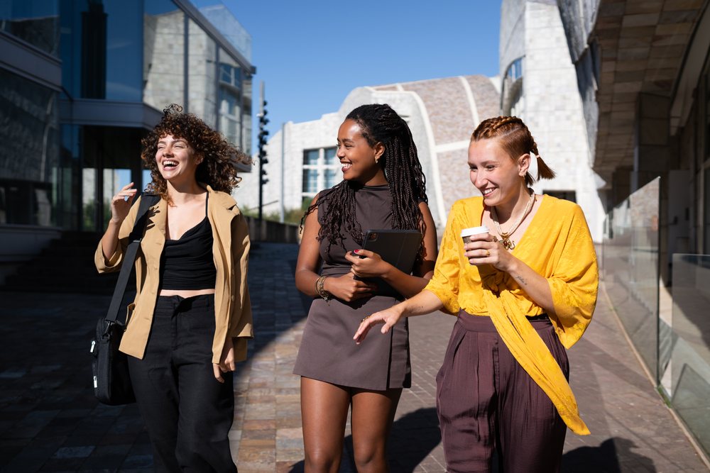 Three young African American and white women laughing and walking