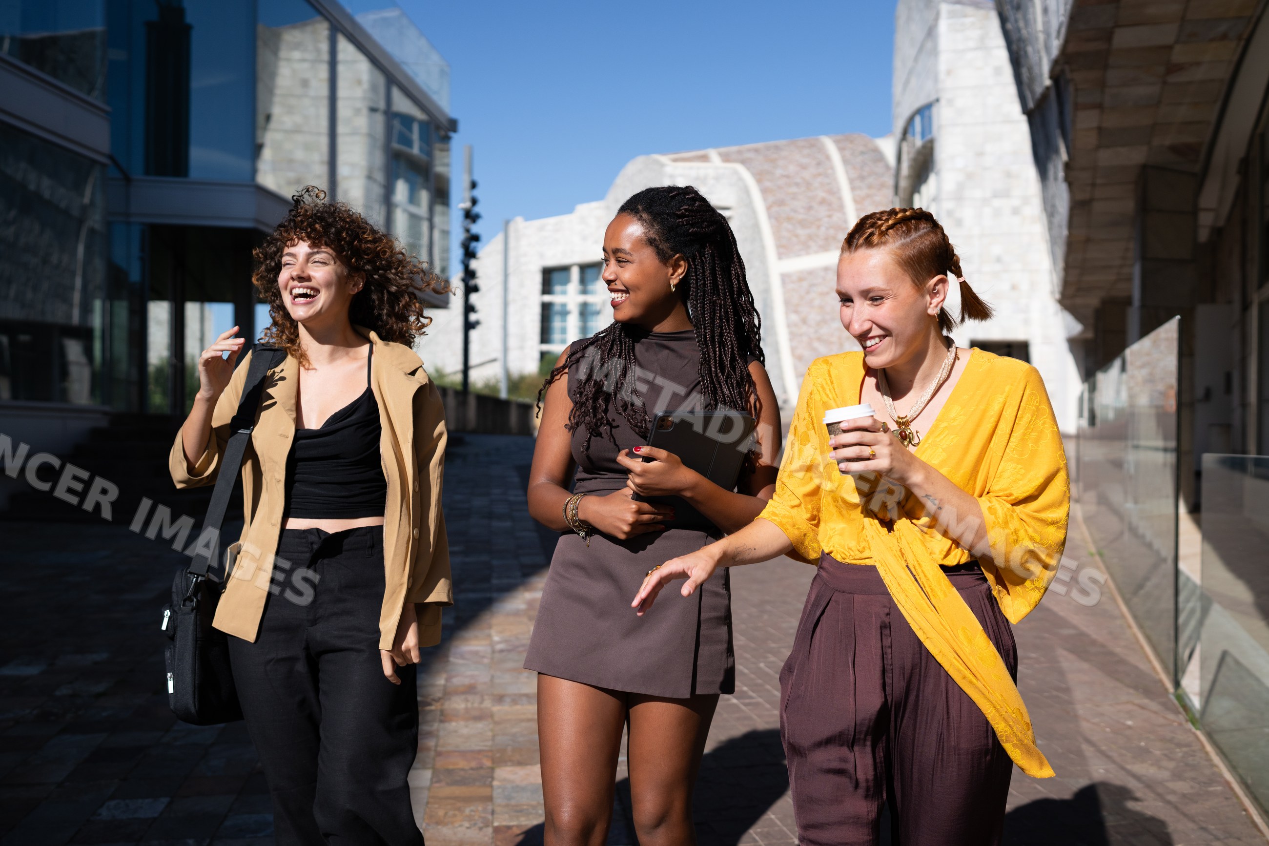 Three young African American and white women laughing and walking