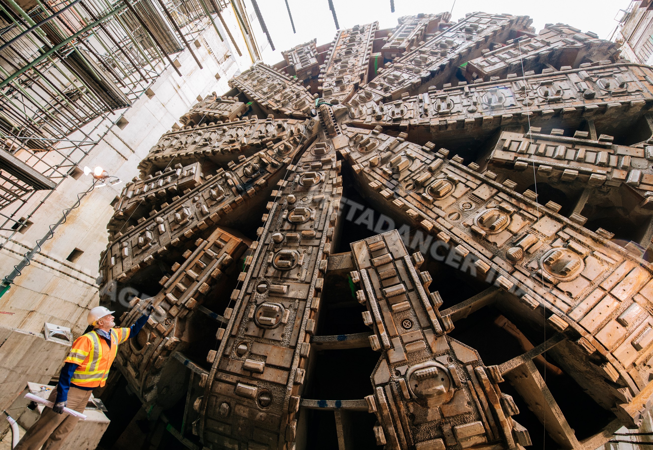 Two construction white workers inspect a tunnel boring machine