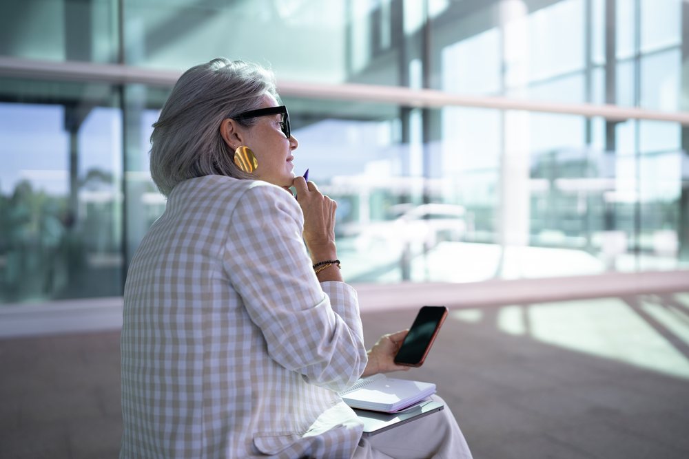 Businesswoman with smartphone and notebook in modern office space