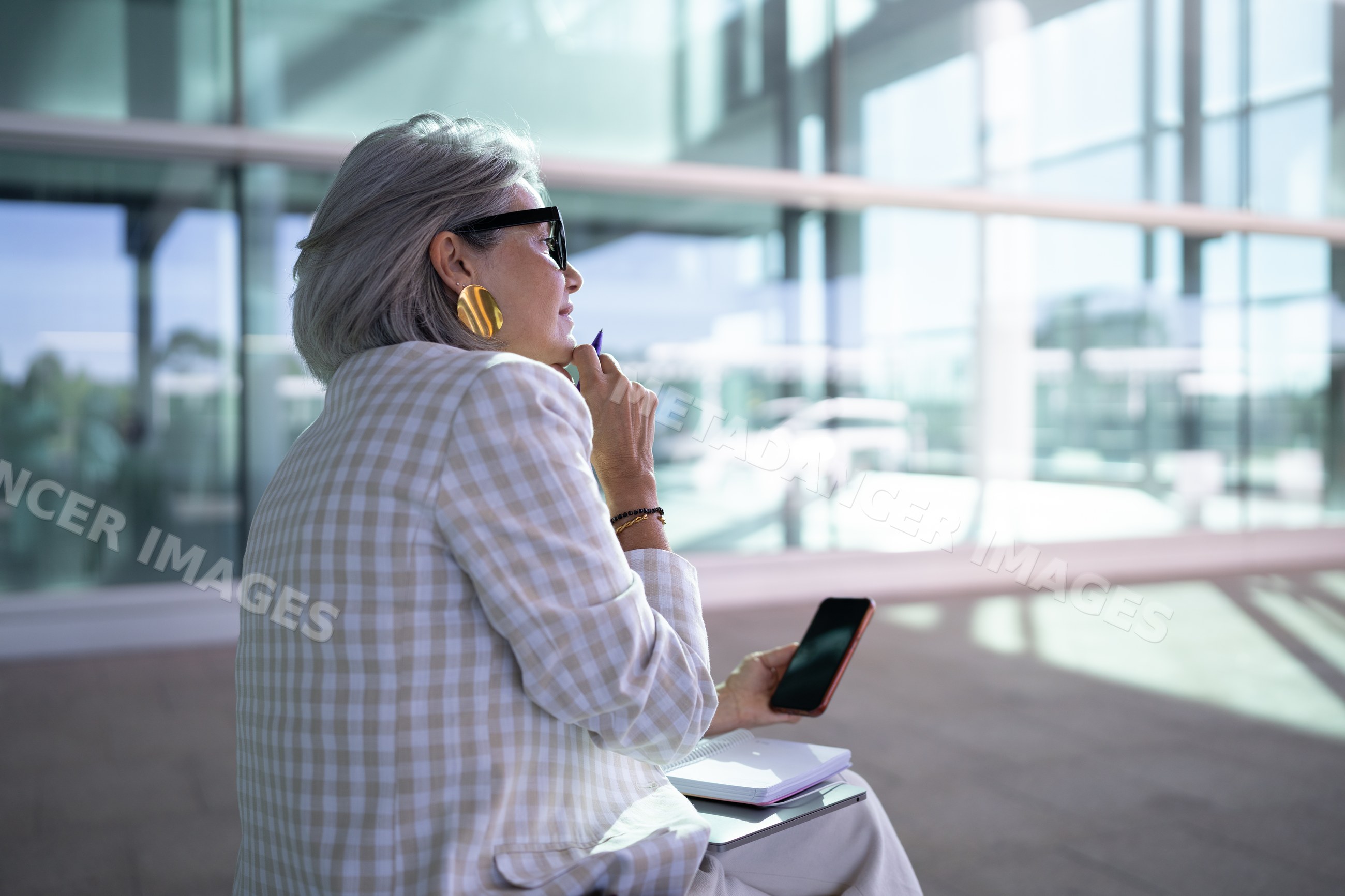 Businesswoman with smartphone and notebook in modern office space