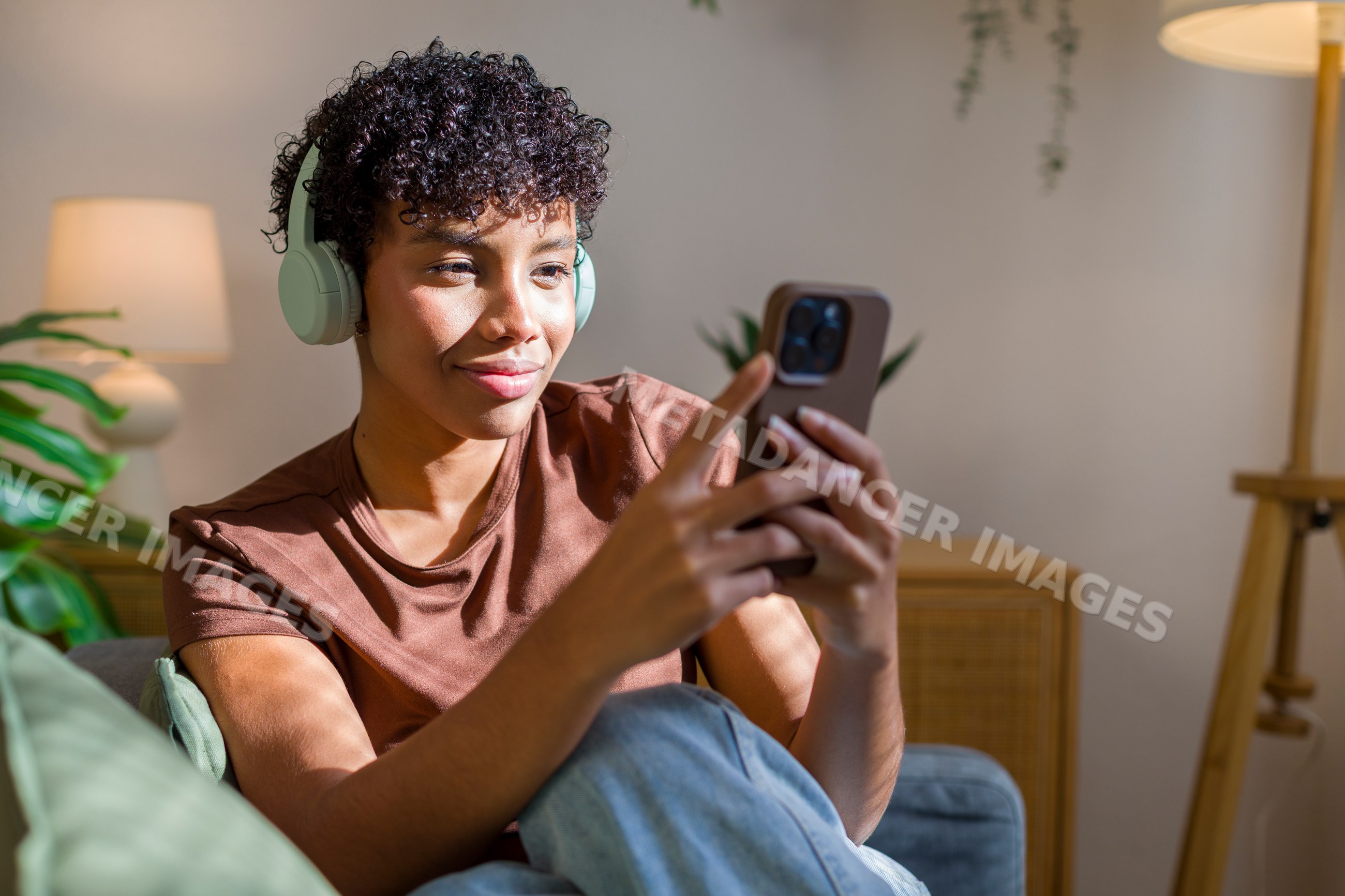 African American woman listening to music with headphones on sofa