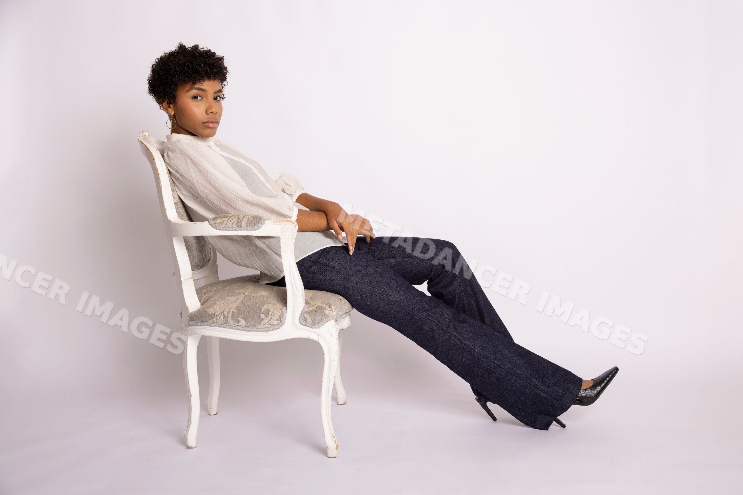 Young Hispanic woman sitting on vintage chair in fashion studio
