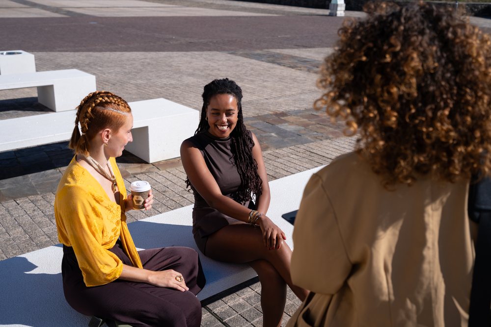 African American and white women chatting and relaxing on bench
