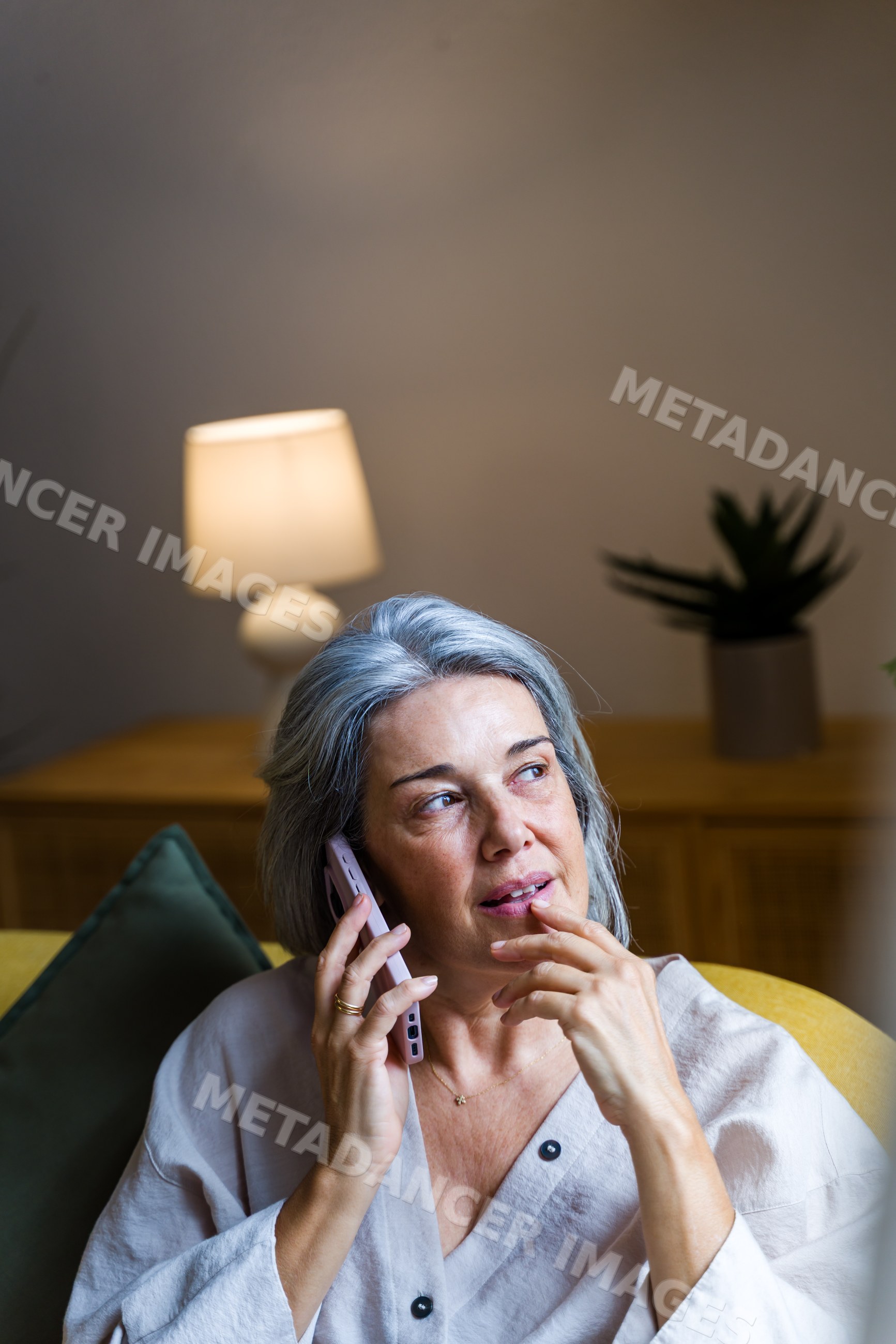 White woman with gray hair talking on phone in home living room