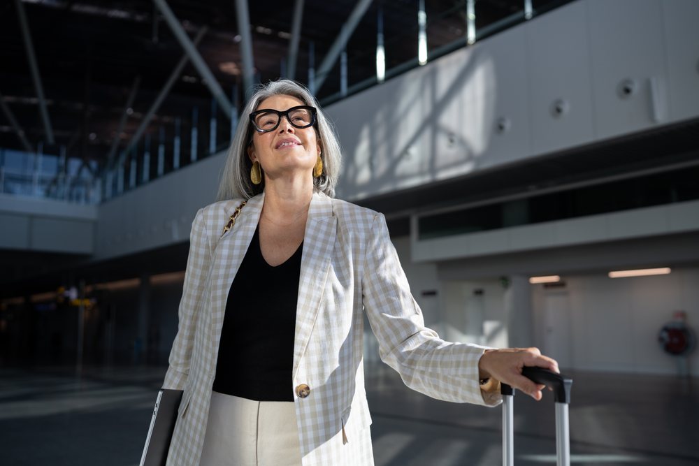 Businesswoman with suitcase and laptop in airport terminal