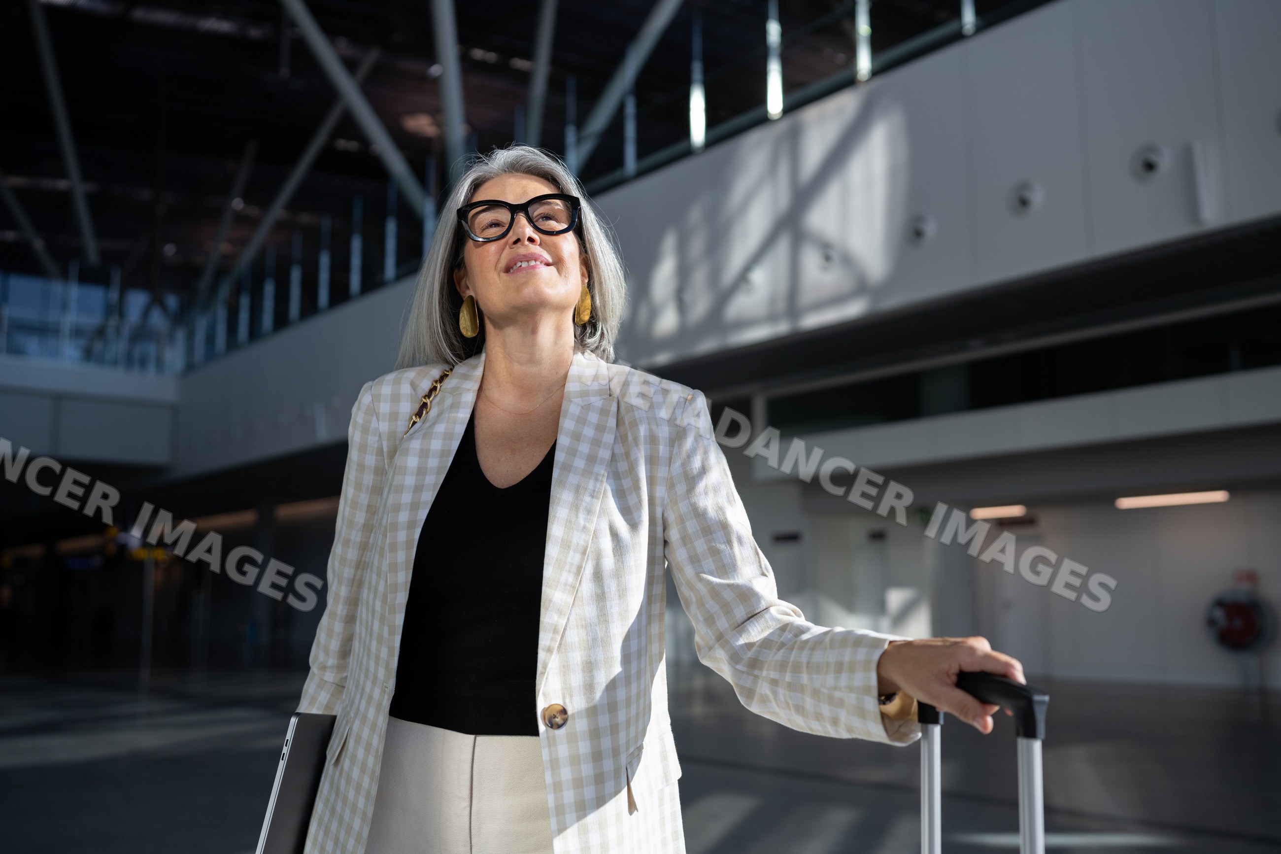 Businesswoman with suitcase and laptop in airport terminal
