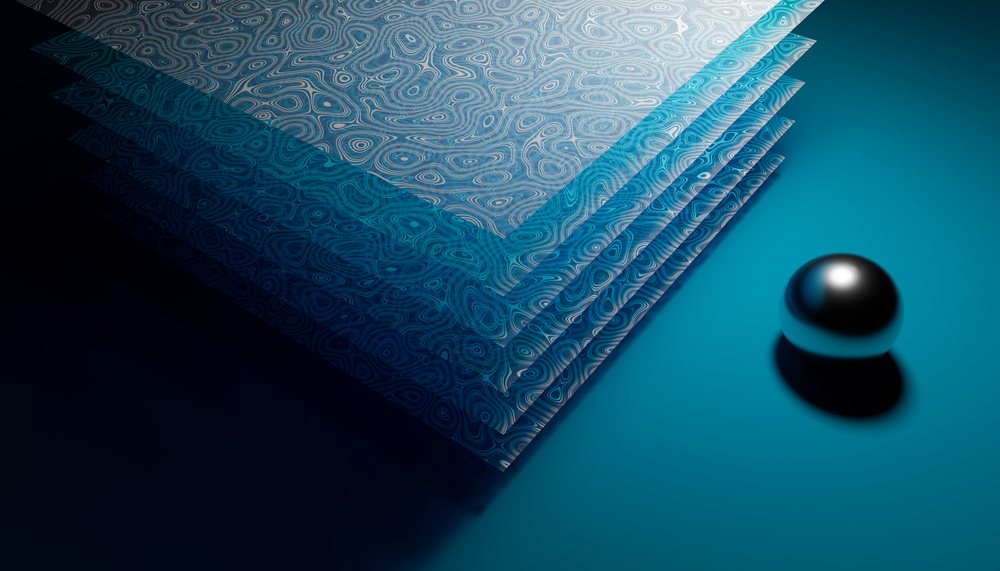 Stack of patterned papers with a metal reflective ball on blue surface