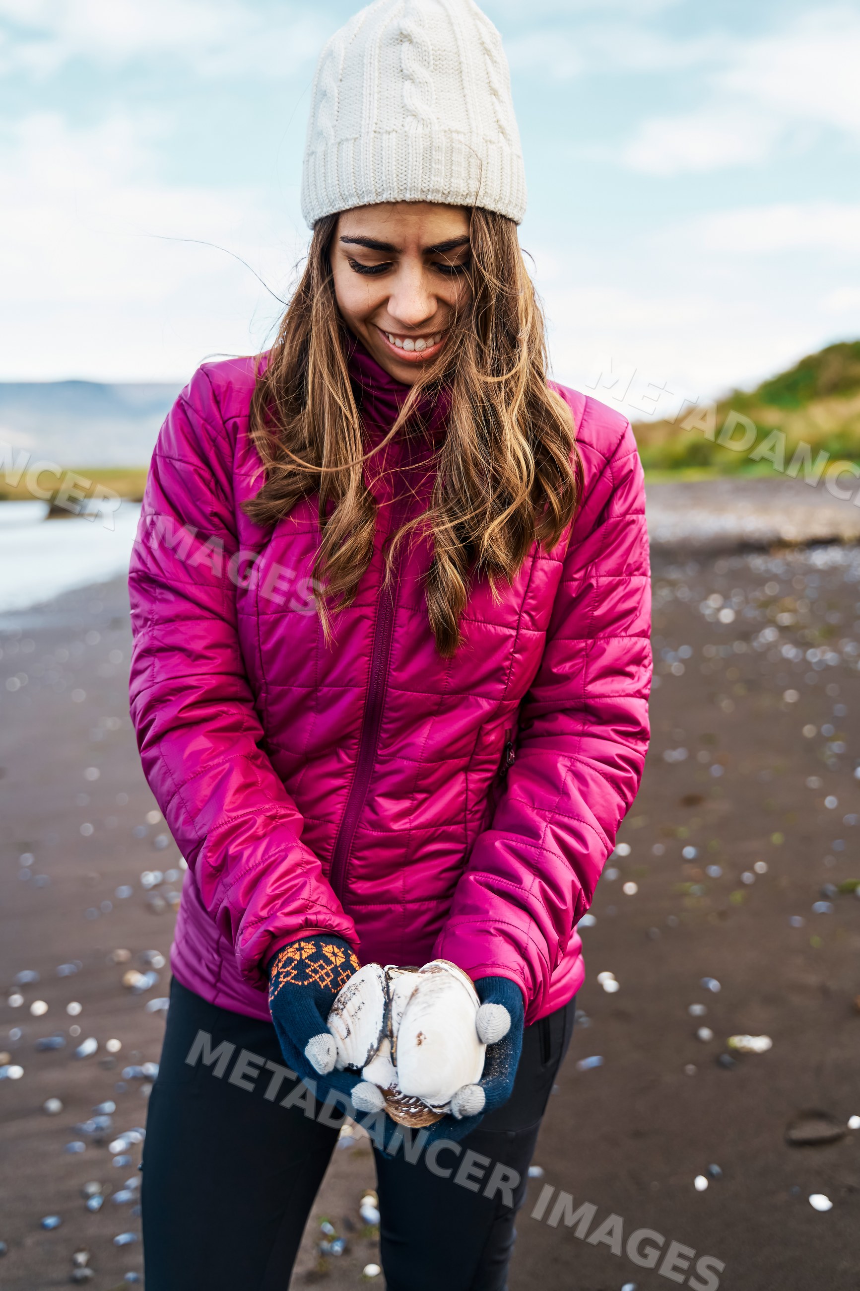 A white woman holds seashells on a beach in Iceland enjoying nature
