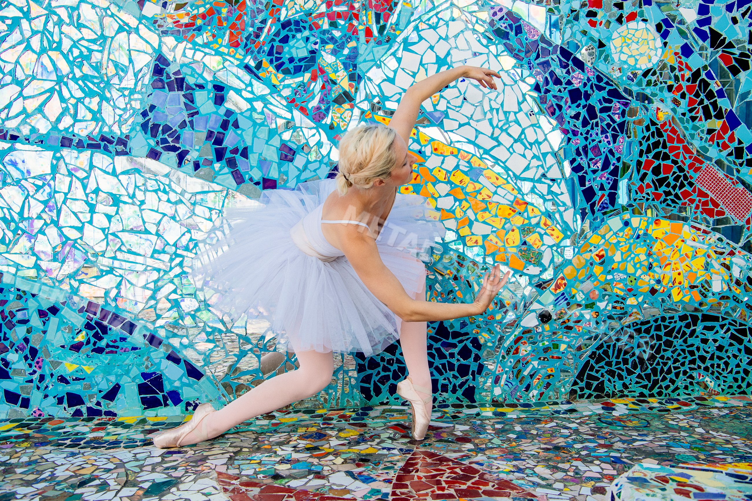 Ballet white dancer performing in front of mosaic wall