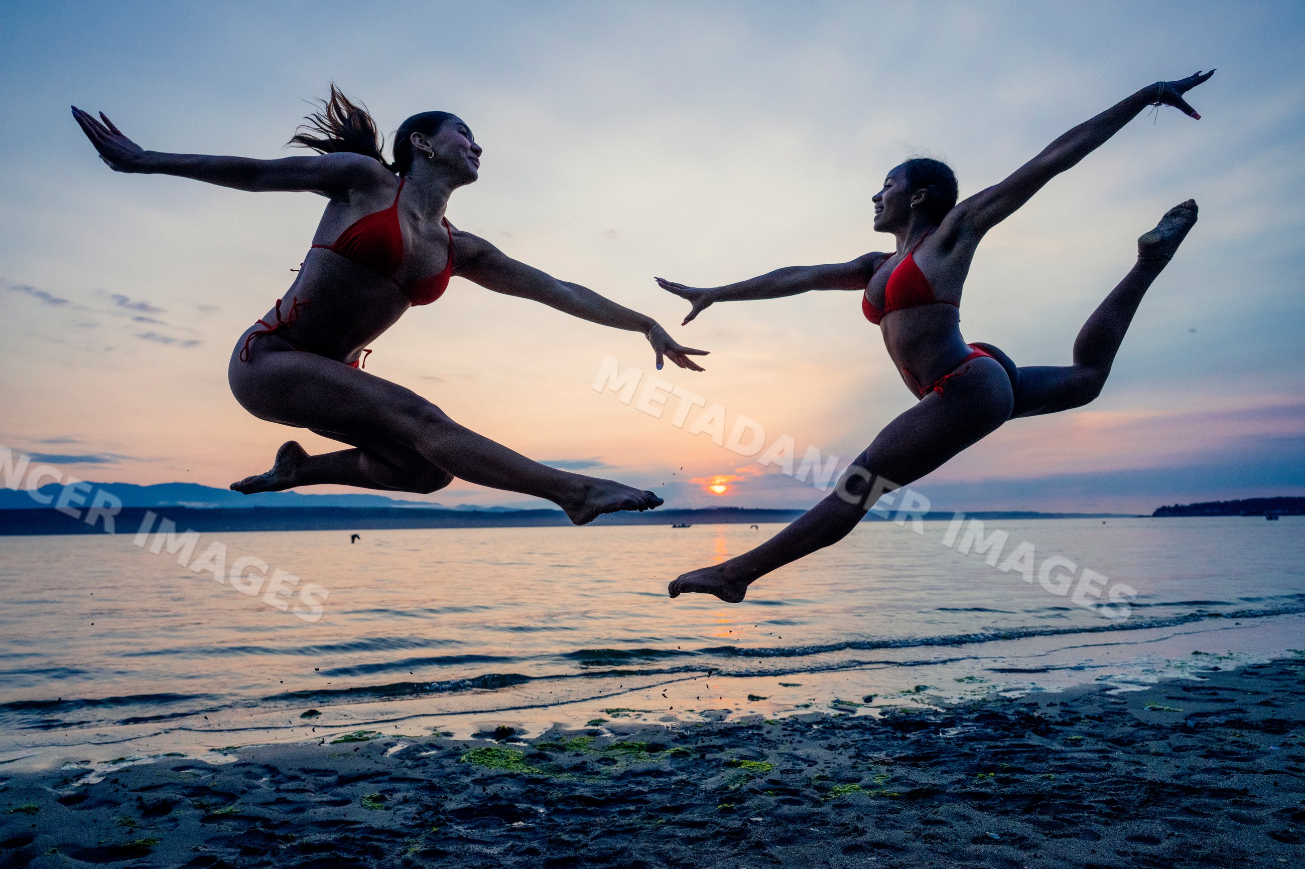 Two women perform partner acrobatics jumping on a beach