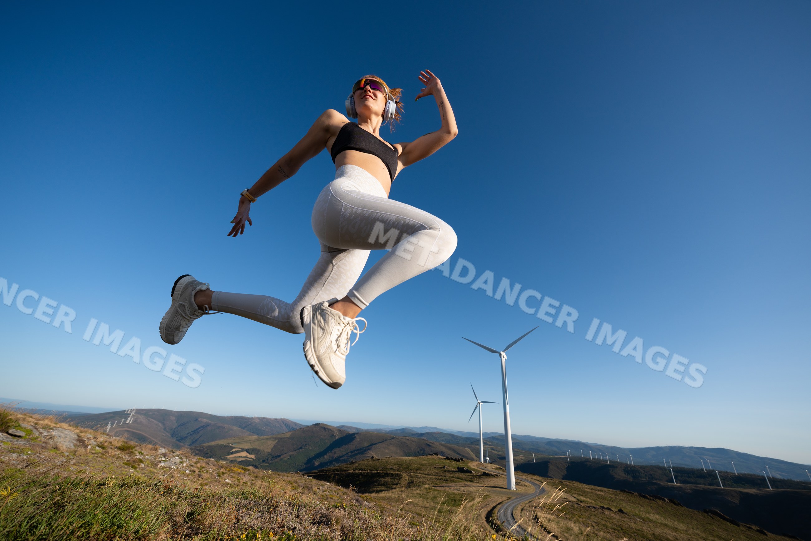 A white woman jumps energetically outdoors