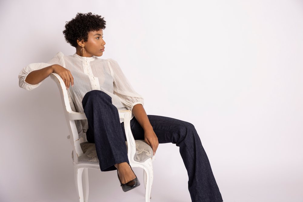 Hispanic woman with curly hair sitting on vintage chair