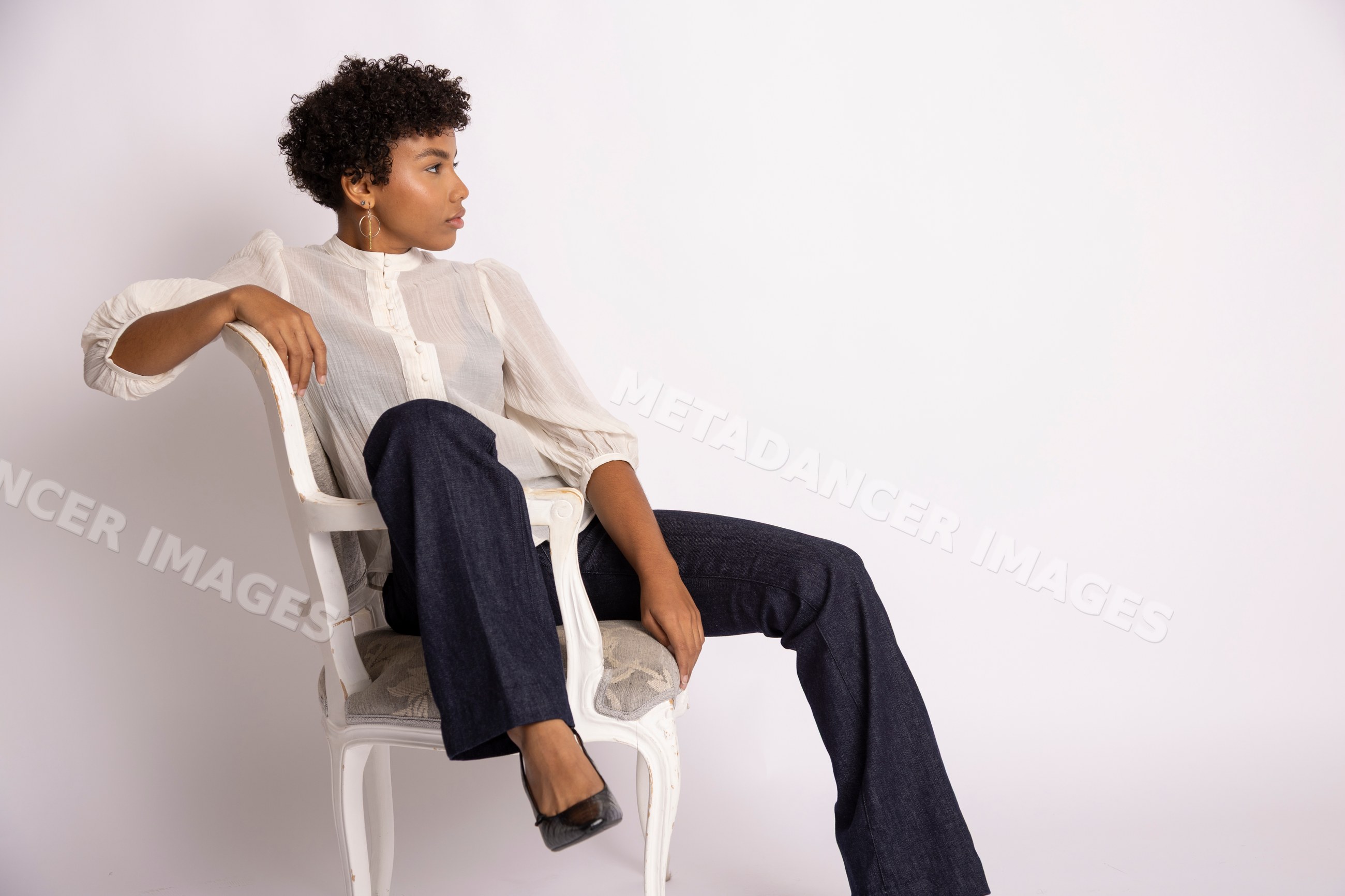 Hispanic woman with curly hair sitting on vintage chair