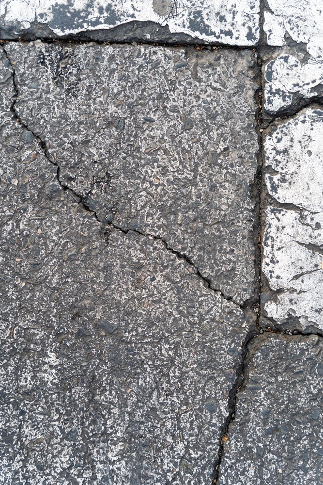 Cracked asphalt pavement with faded road markings in urban Spain
