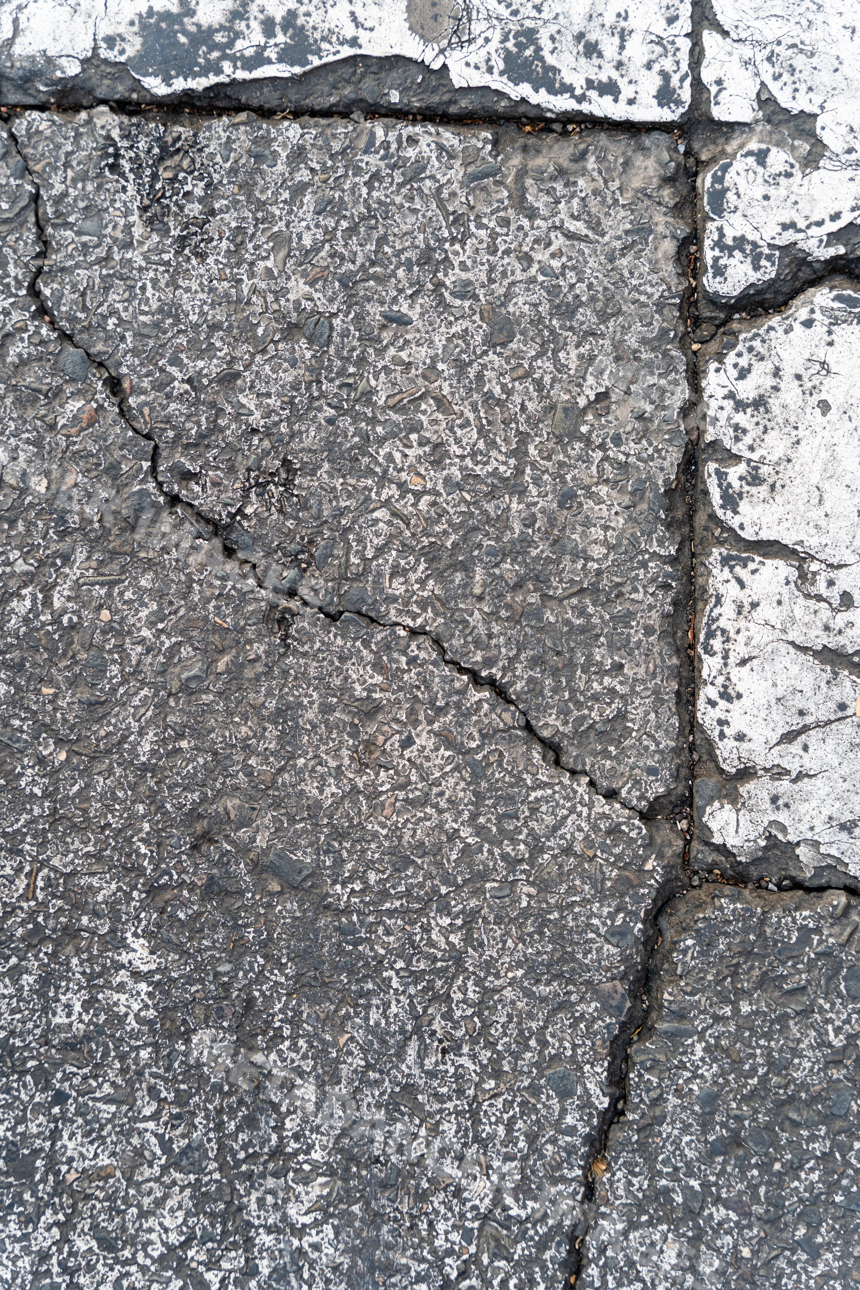Cracked asphalt pavement with faded road markings in urban Spain