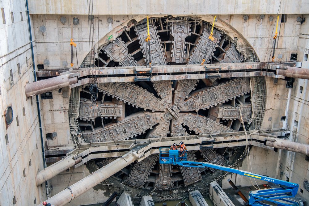 White construction workers operate tunnel boring machine