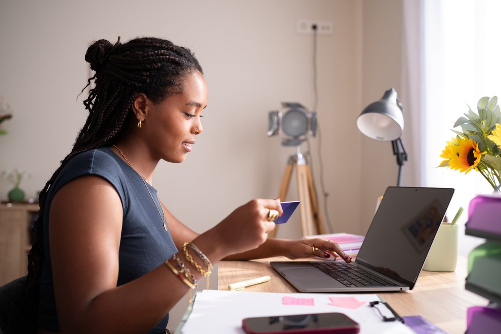 A black African American woman shops online from her laptop