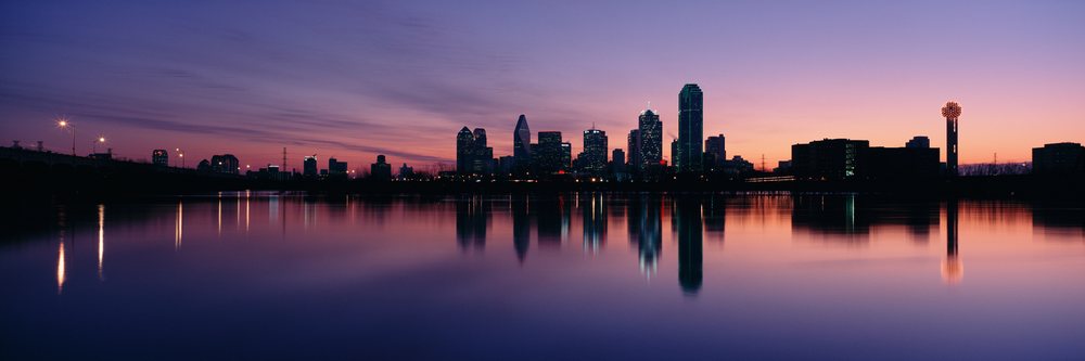 City skyline of dallas, texas at sunset with water reflections