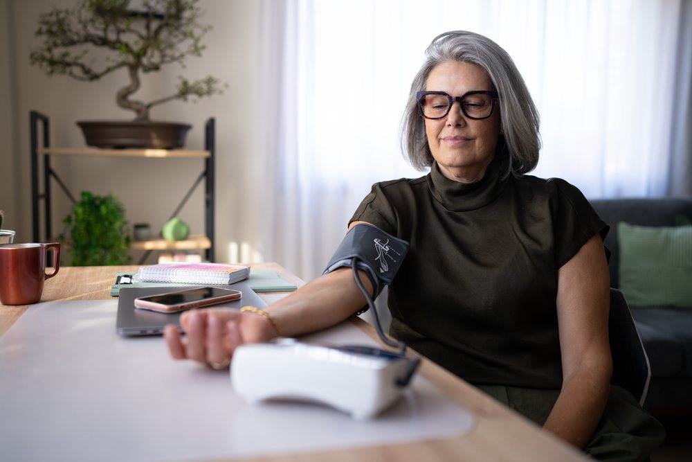 Mature white woman measuring blood pressure at home in living room
