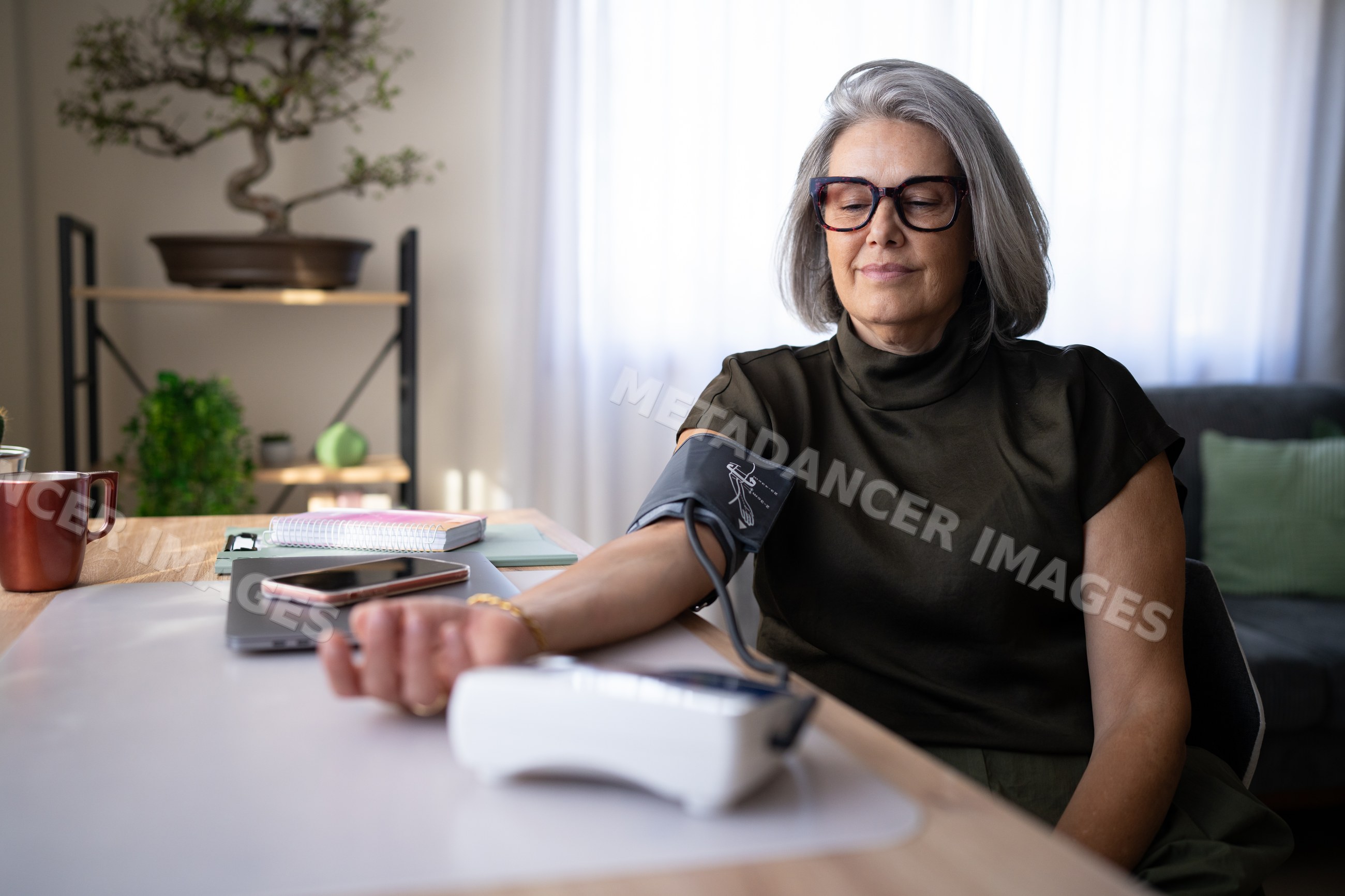 Mature white woman measuring blood pressure at home in living room