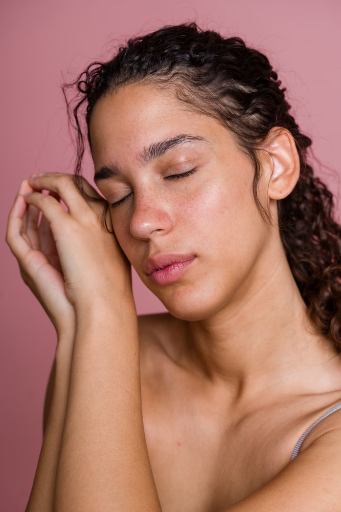 Young Hispanic woman with closed eyes resting face on hands