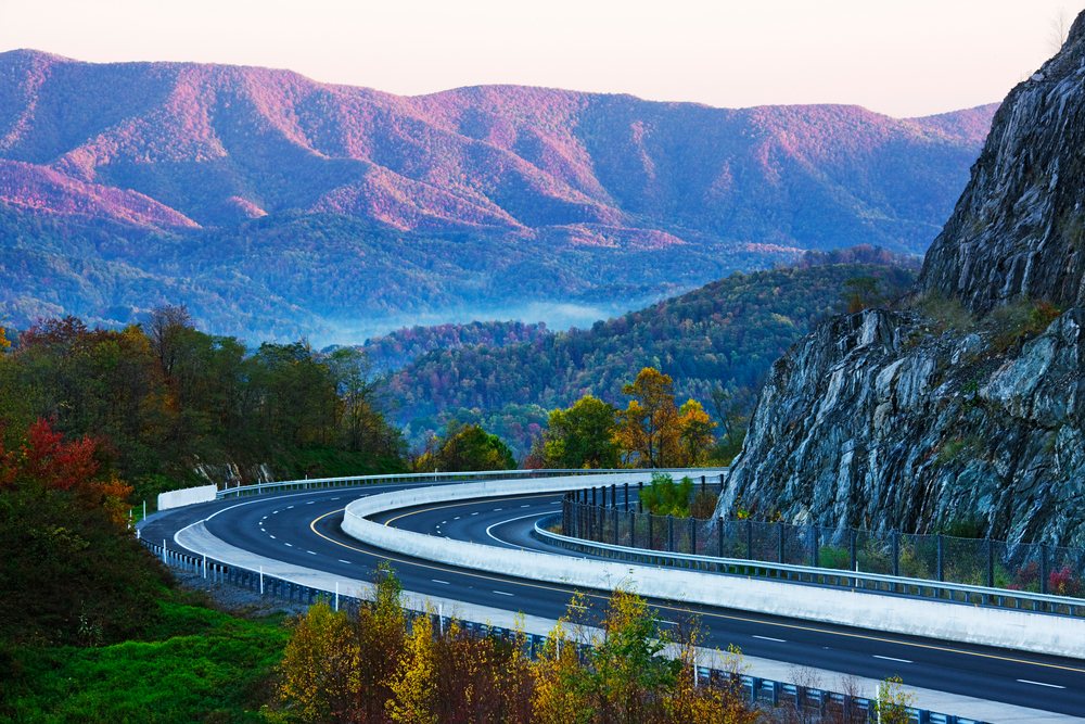 Curved highway winding through autumn forest and mountains