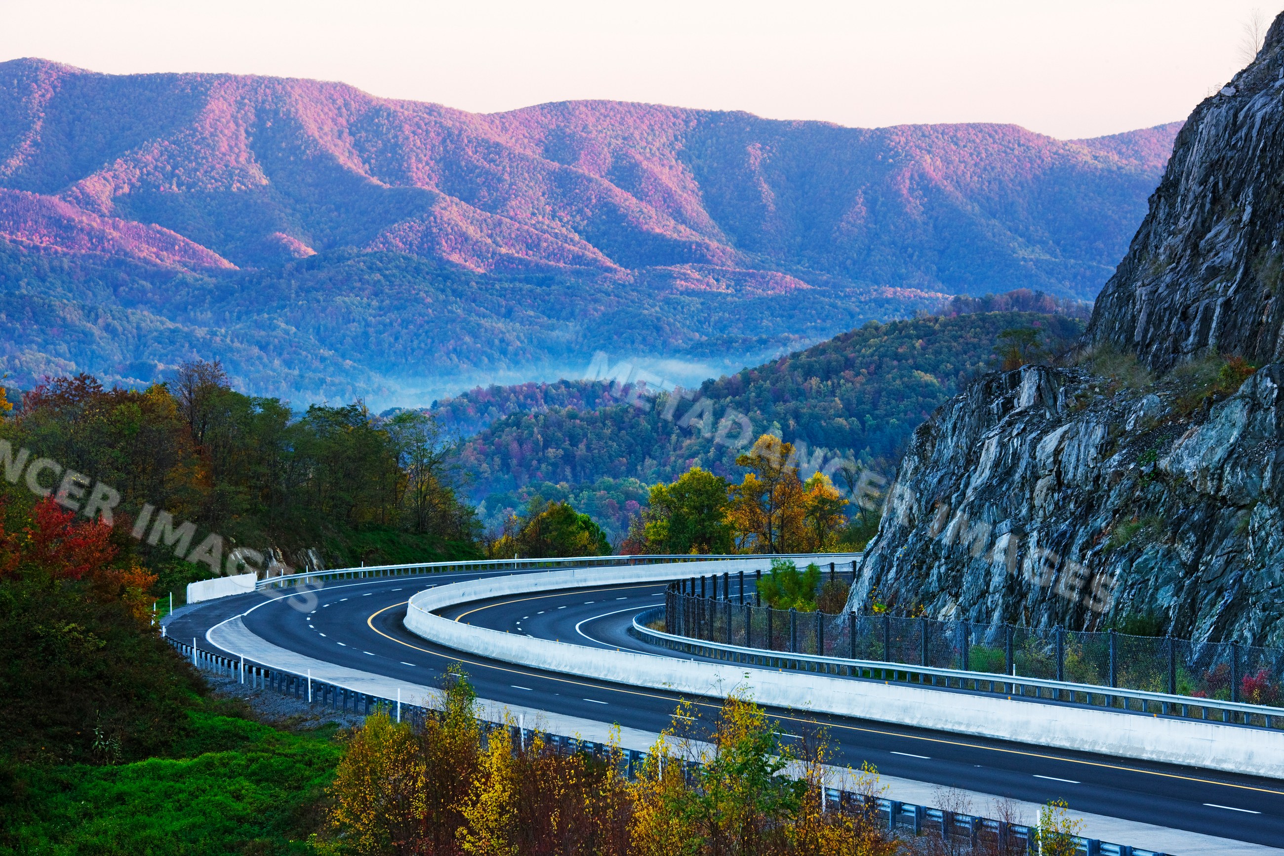 Curved highway winding through autumn forest and mountains
