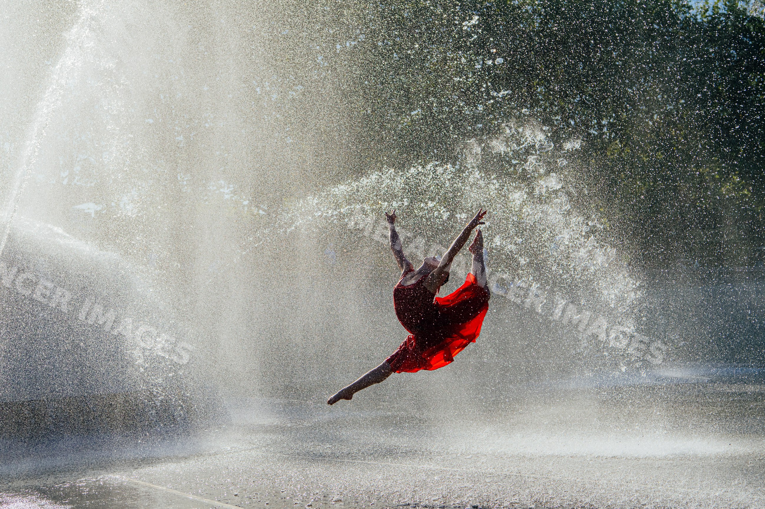 White dancer leaping through water spray from outdoor fountain